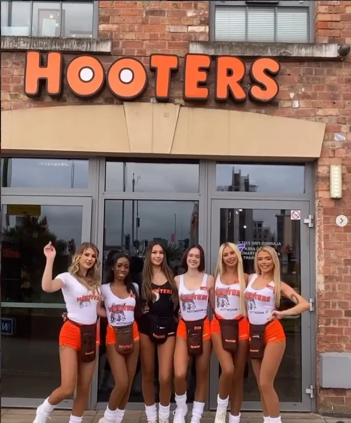 Hooters restaurant with six female employees standing in front of the entrance.
