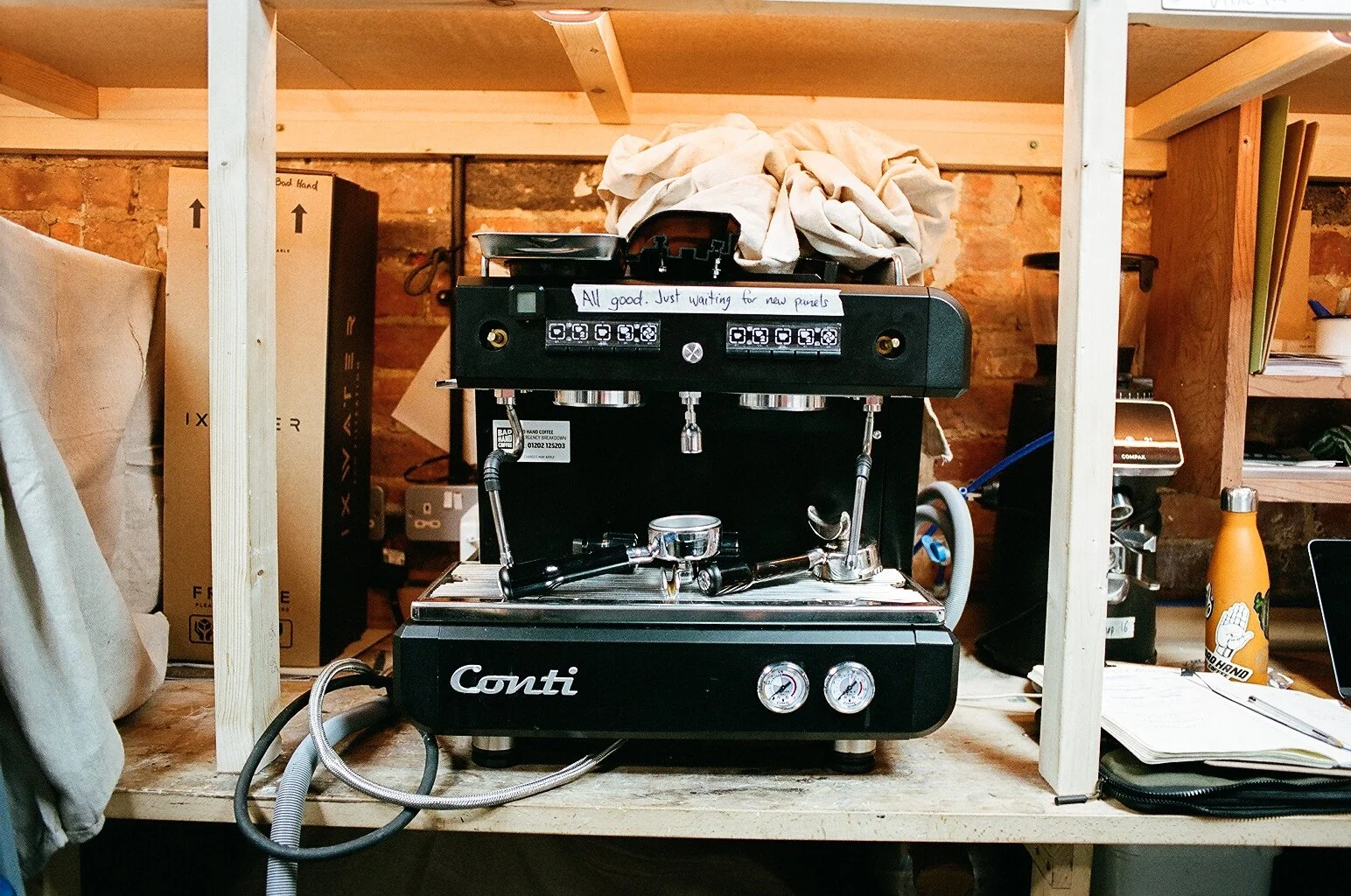 Black Conti commercial espresso machine stored on a wooden shelf in the coffee workspace. Photo by Shahab Notghi.