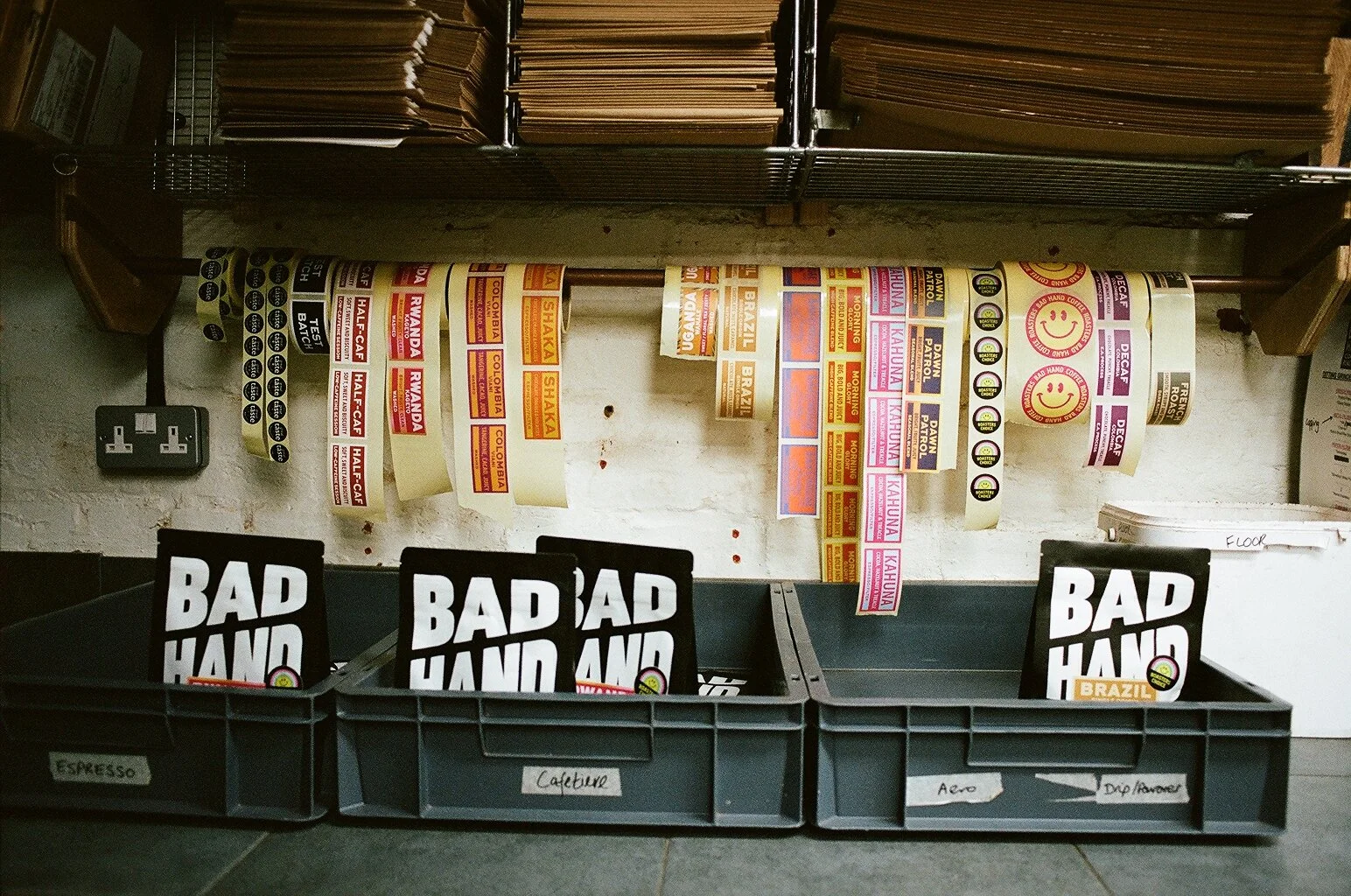 Coffee origin labels and Bad Hand Coffee packaging organised in storage trays at the roastery. Photo by Shahab Notghi.