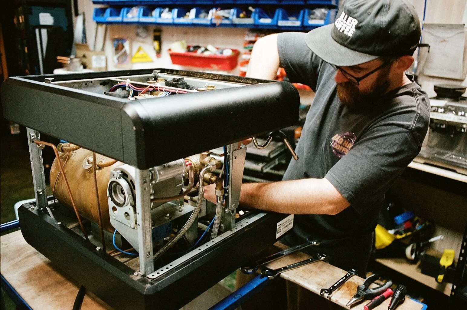 Close-up of a technician repairing the internal components of a commercial coffee machine. Photo by Shahab Notghi.