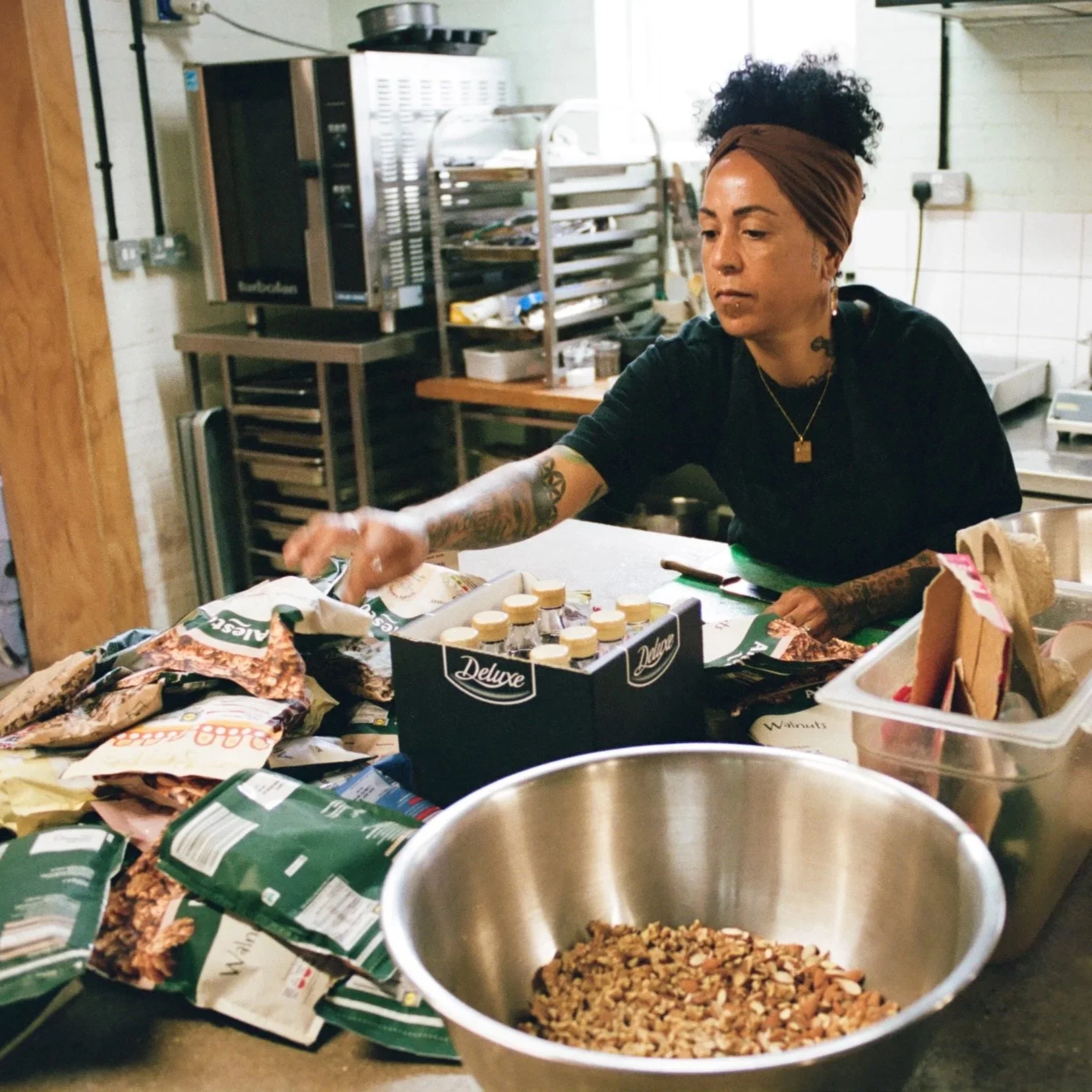 Chef organising baking ingredients and nuts on a work surface in a commercial vegan kitchen. Photo by Shahab Notghi.