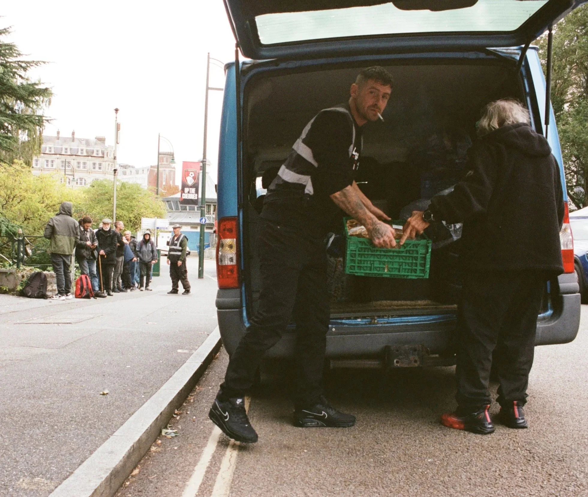 Emotional candid shot showing human interaction and community connection between a volunteer and a resident at the Boscombe support hub.