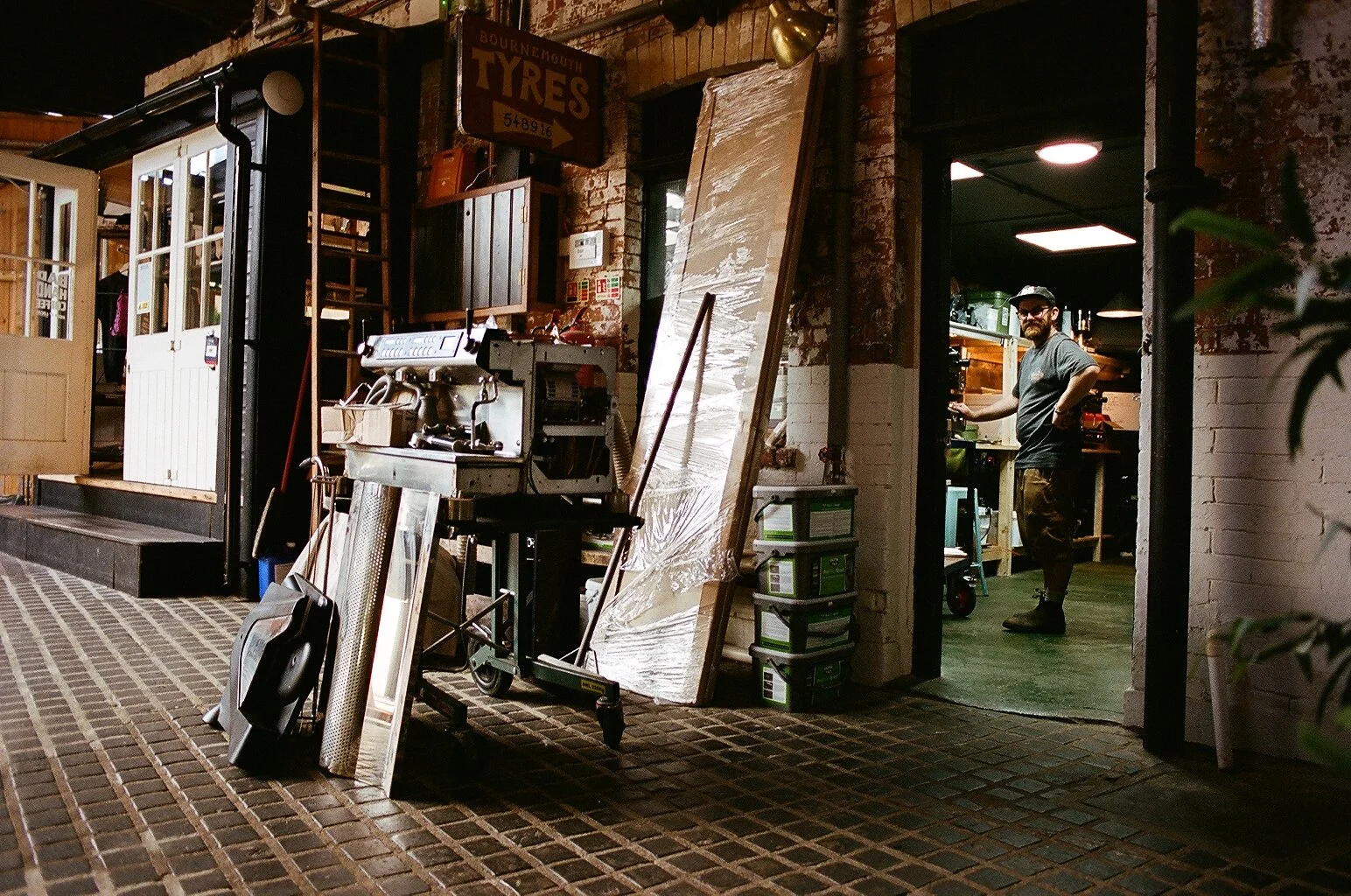 Industrial warehouse entrance with vintage signage, equipment and a coffee workshop in the background. Photo by Shahab Notghi.