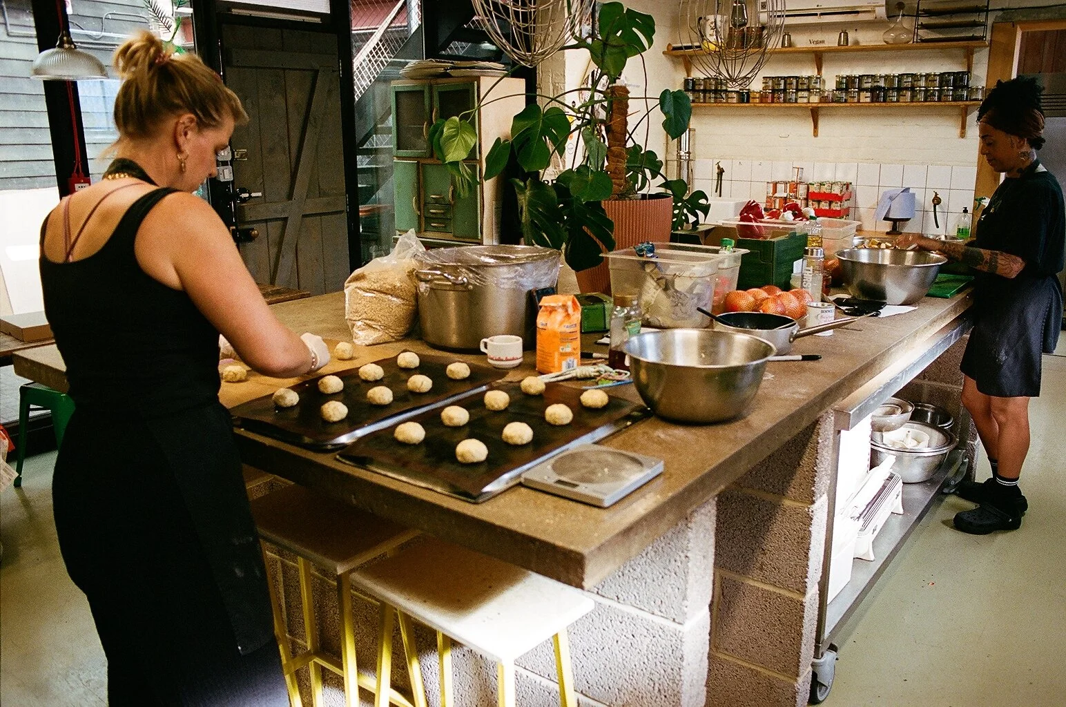 Kitchen staff shaping dough on baking trays while preparing food in a commercial kitchen. Photo by Shahab Notghi.
