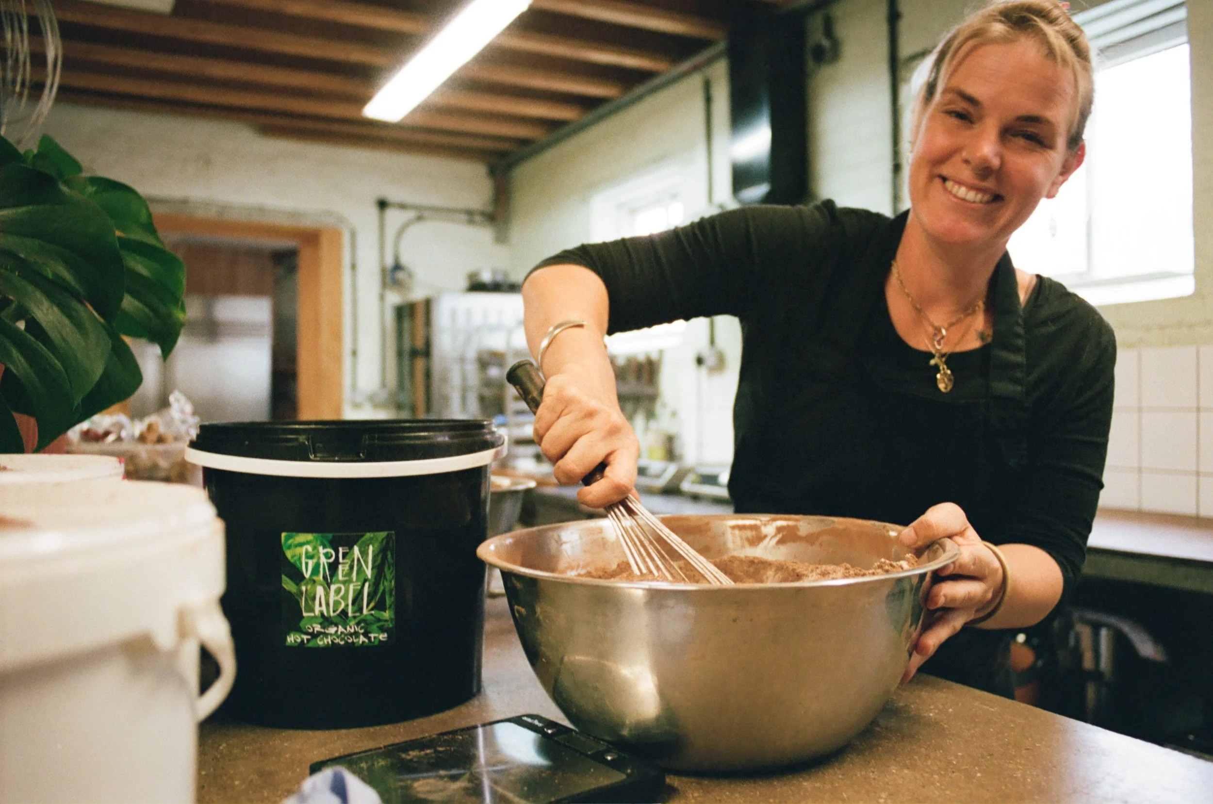 Chef mixing ingredients in a large metal bowl at the Green Label Kitchen workspace. Photo by Shahab Notghi.