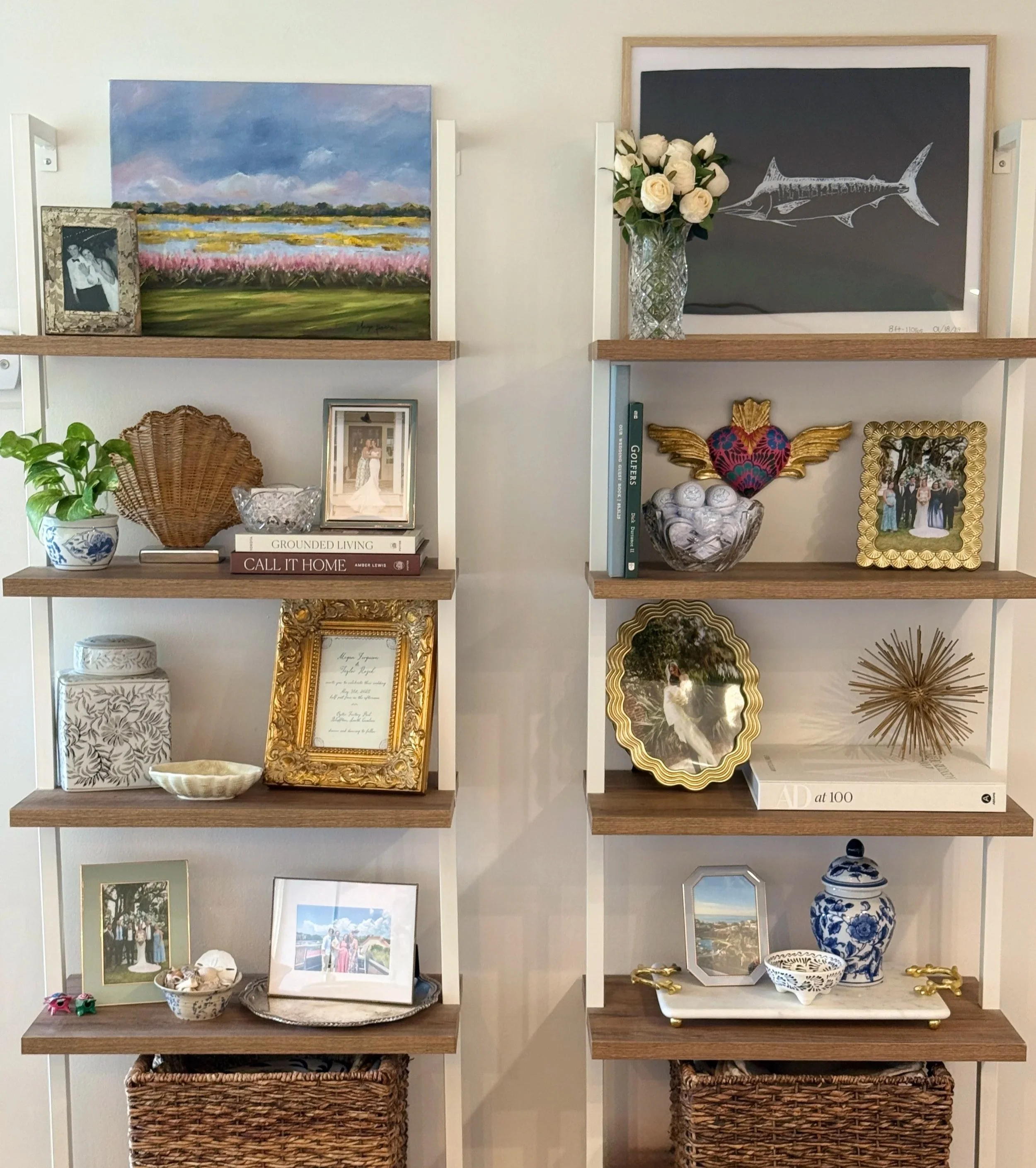 White shelving unit with decorative items including framed photos, paintings, plants, vases, figurines, and woven baskets.