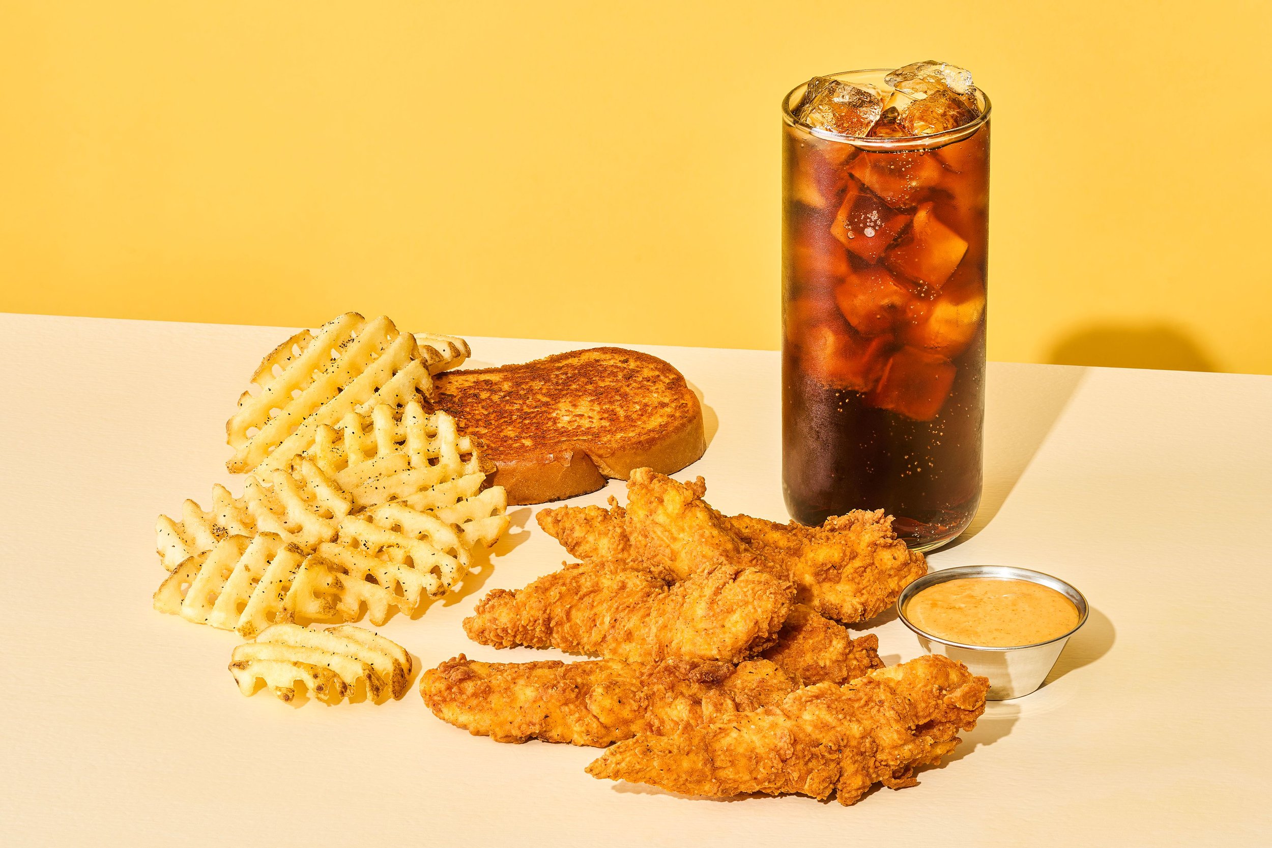 Five crispy chicken tenders served with fries, garlic Parmesan toast, a Coca-Cola, and sweet sriracha sauce
