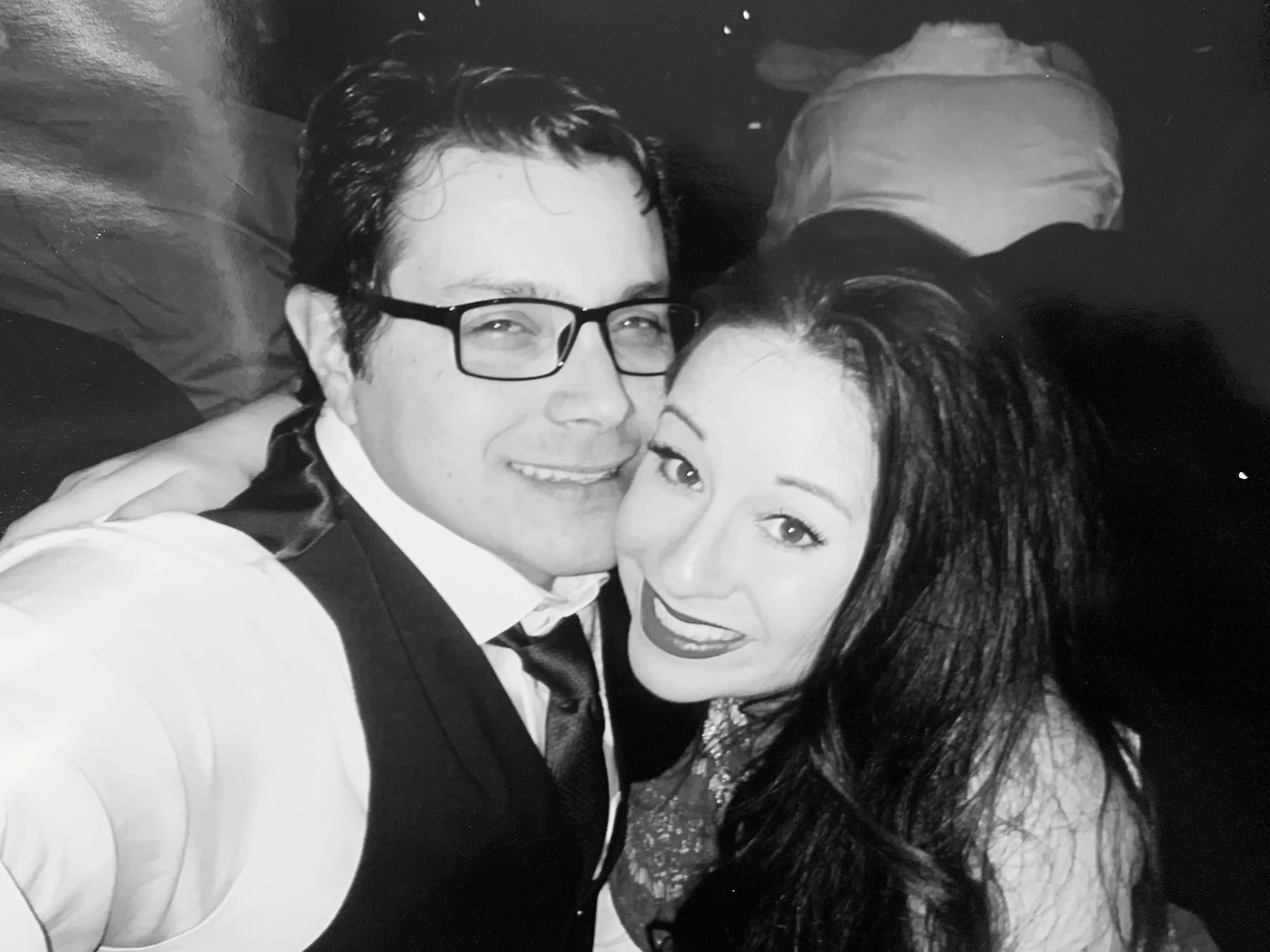 Black-and-white photo of a smiling couple posing close together.