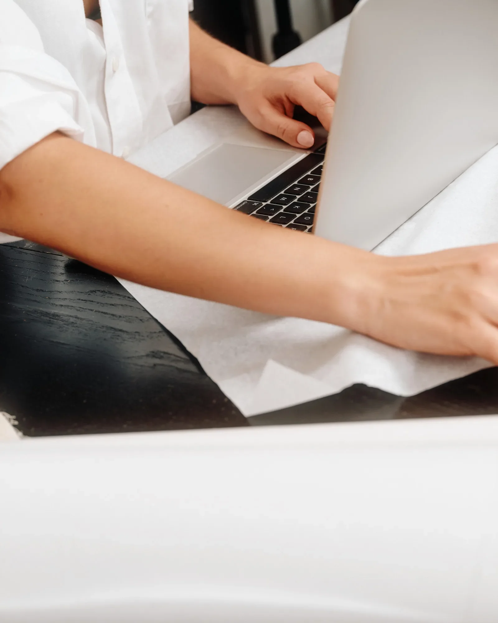 Close-up of hands typing on a laptop keyboard at a desk