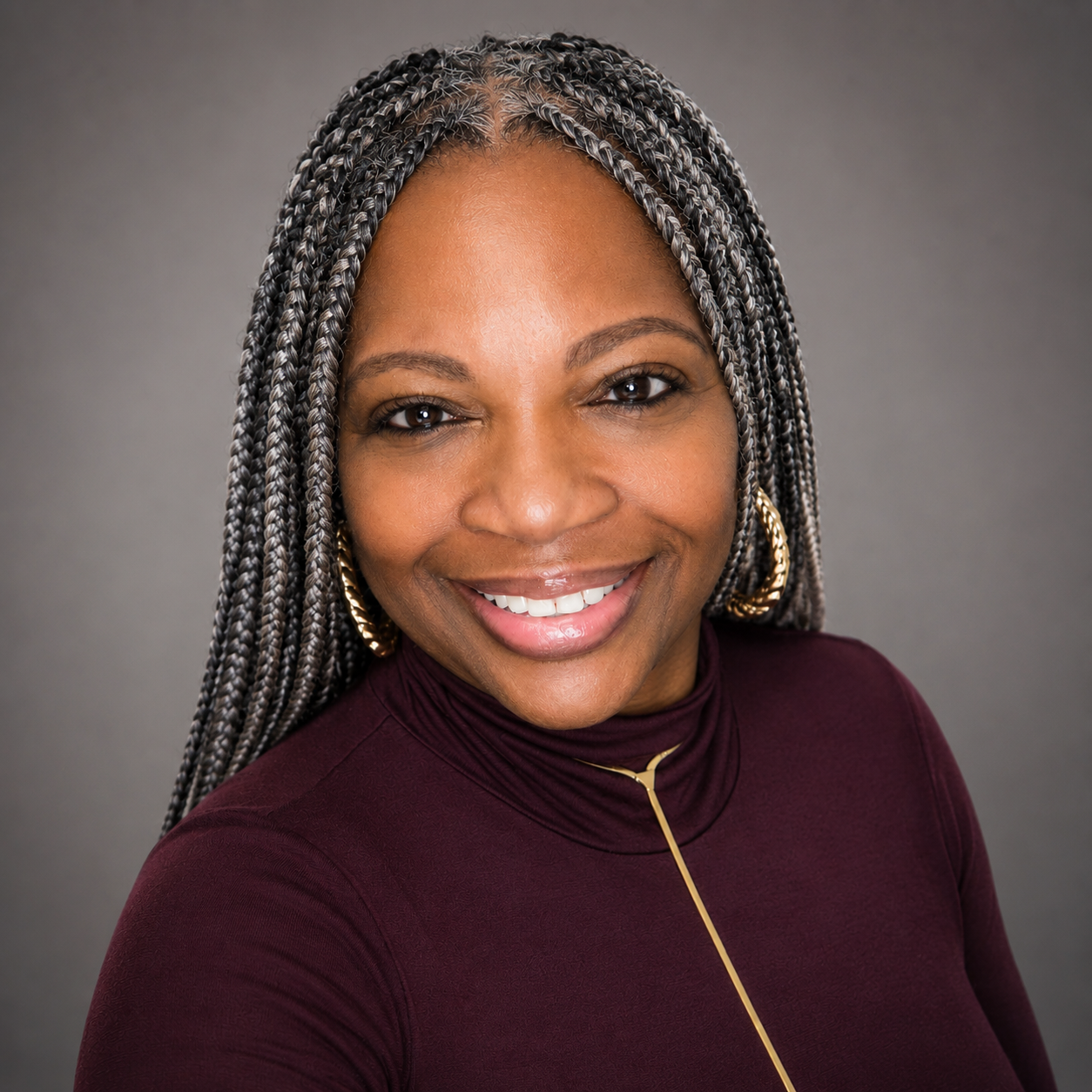 Photo of True Consulting Firm Founder Kenya Dalton with long gray-and-black box braids, earrings, and a burgundy top against a gray background