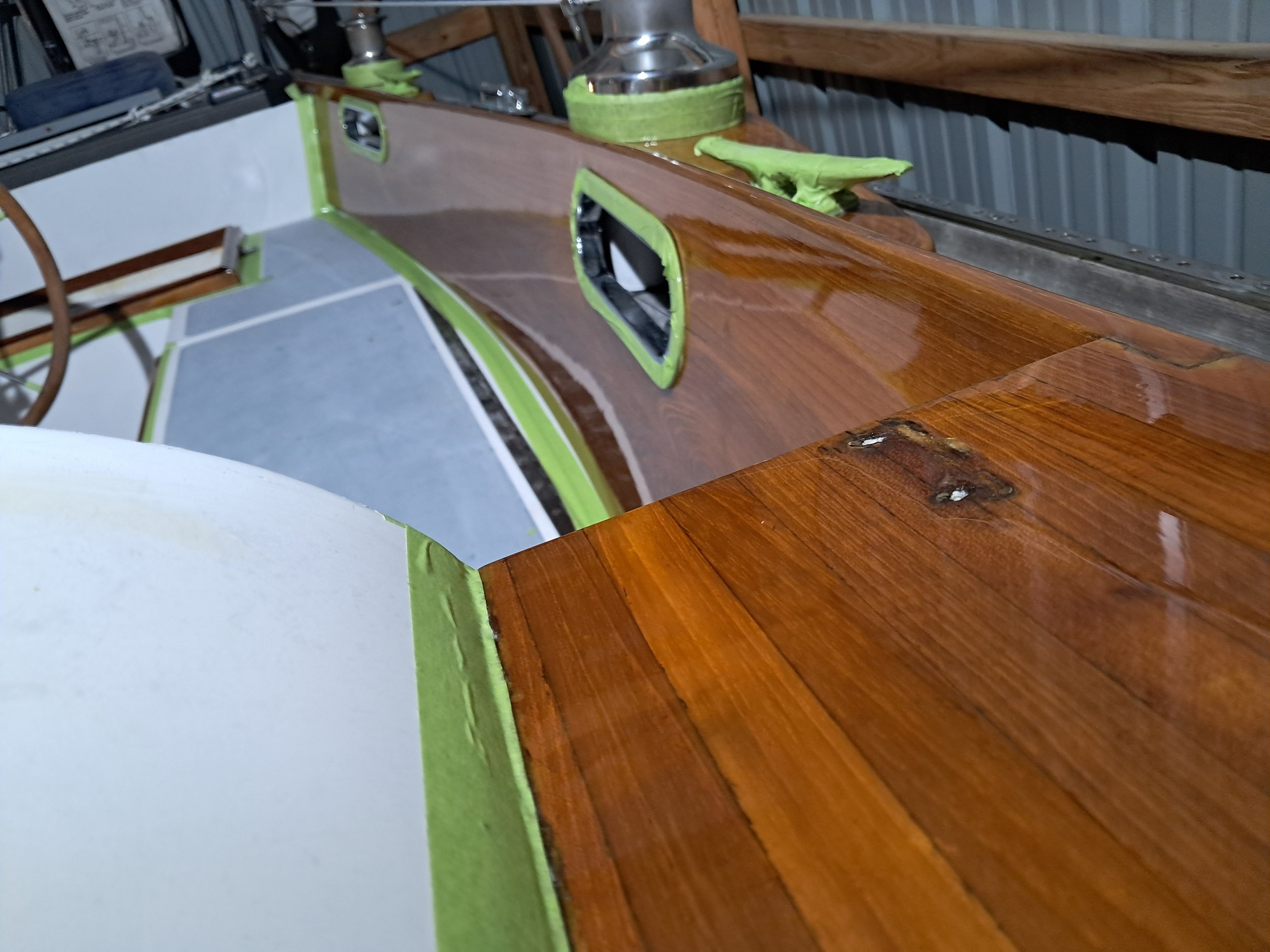 this image shows part of the cockpit of a sailboat showcasing freshly varnished wood on a marine vessel
