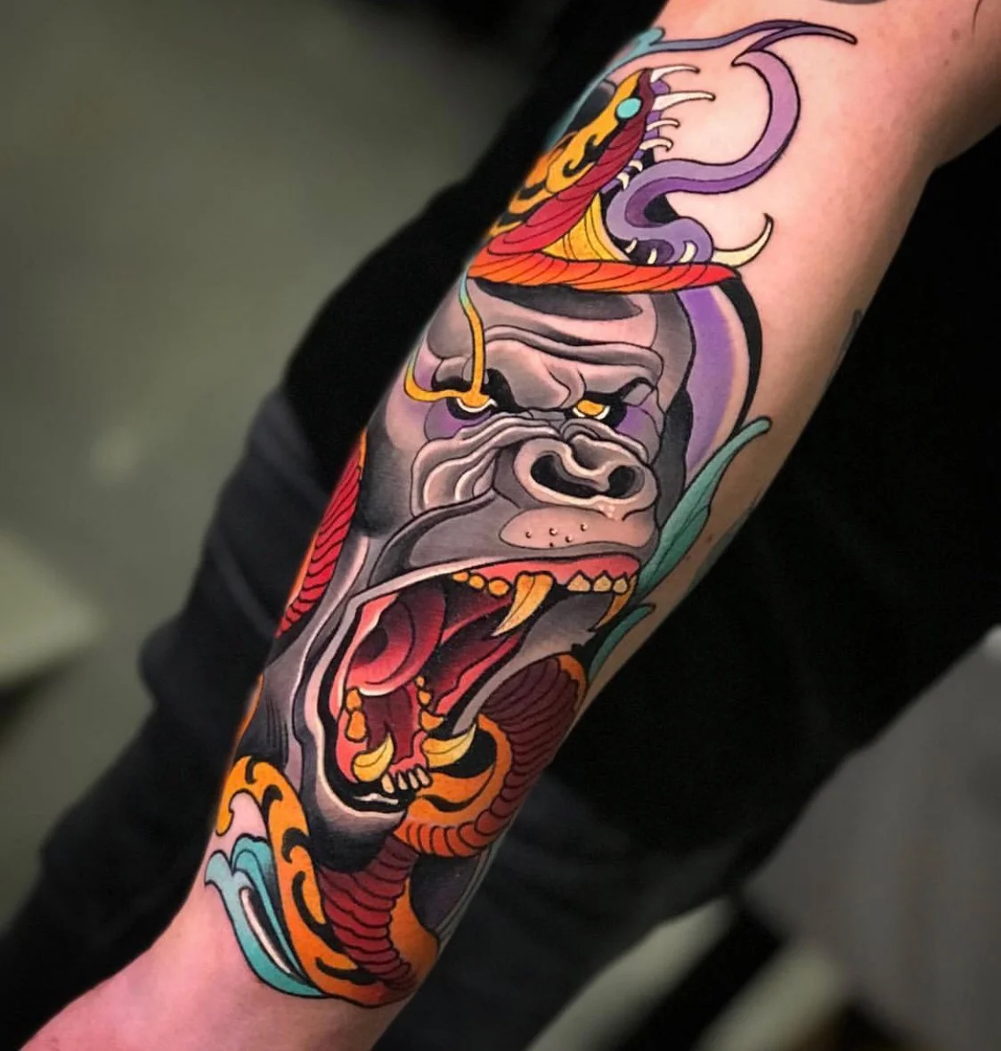 Colorful tattoo of a gorilla with an open mouth, surrounded by stylized waves and flames on an arm. By Johnny Domus, Neo Traditional and Neo Japanese Tattoo.