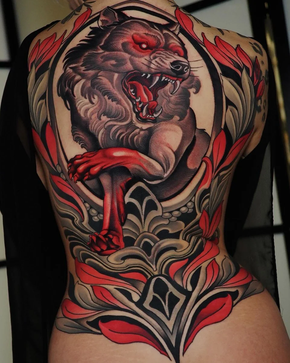 A detailed tattoo of a roaring lion with red eyes on a person's back, surrounded by red and beige floral and decorative elements. By Johnny Domus, Neo Traditional and Neo Japanese Tattoo.