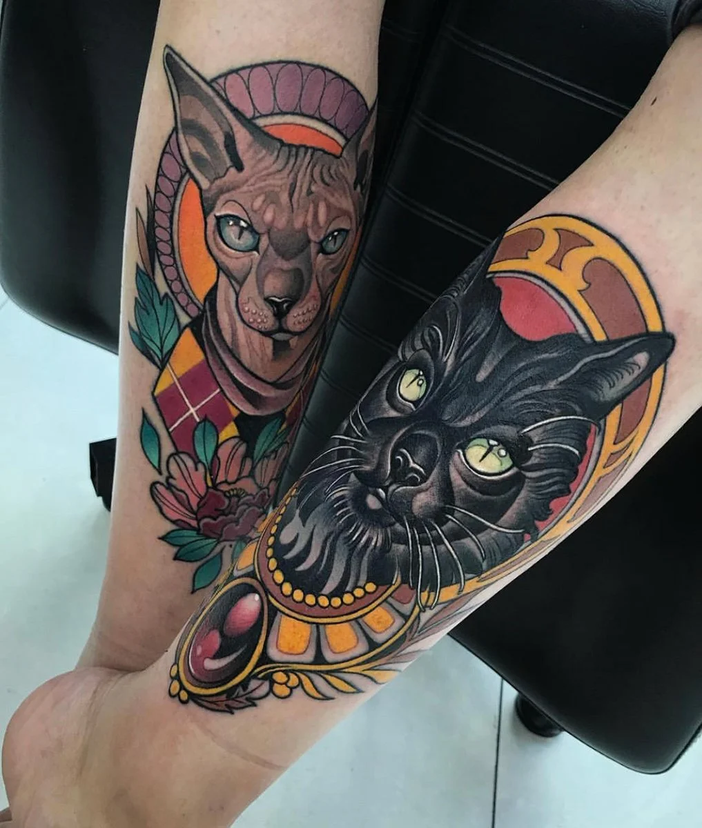 Colorful tattoo of a Sphynx cat with gray fur and blue eyes, and a black cat with yellow eyes, framed by decorative elements. By Johnny Domus, Neo Traditional and Neo Japanese Tattoo.