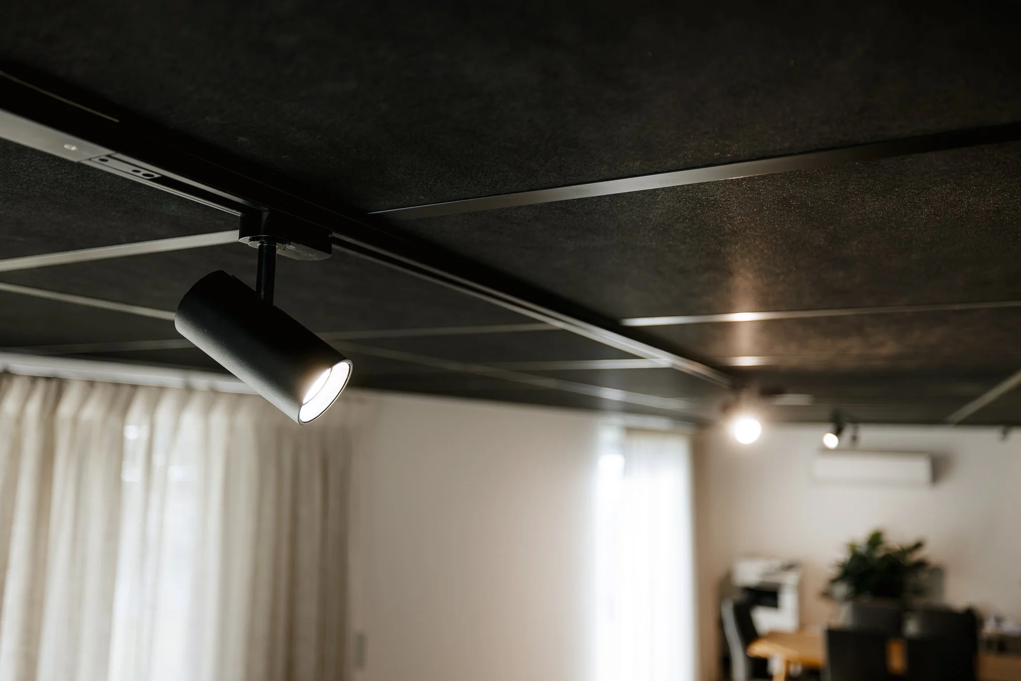 Close-up of a track lighting fixture with an adjustable spotlight, ceiling mounted in commercial office.