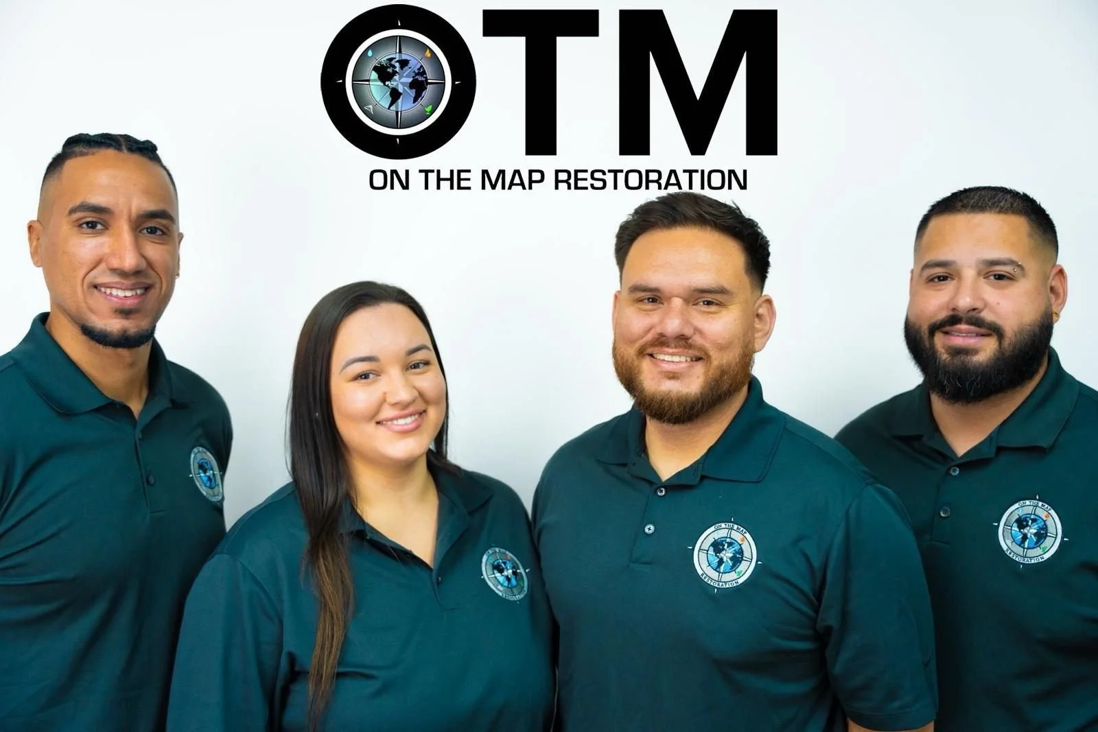 Four people wearing OTM Restoration polos beneath the company logo.