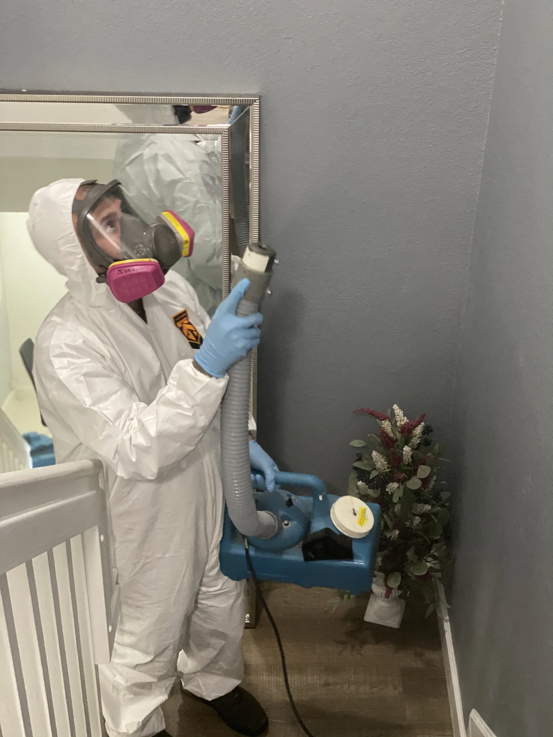 Technician operating a HEPA air scrubber inside a mold remediation work area