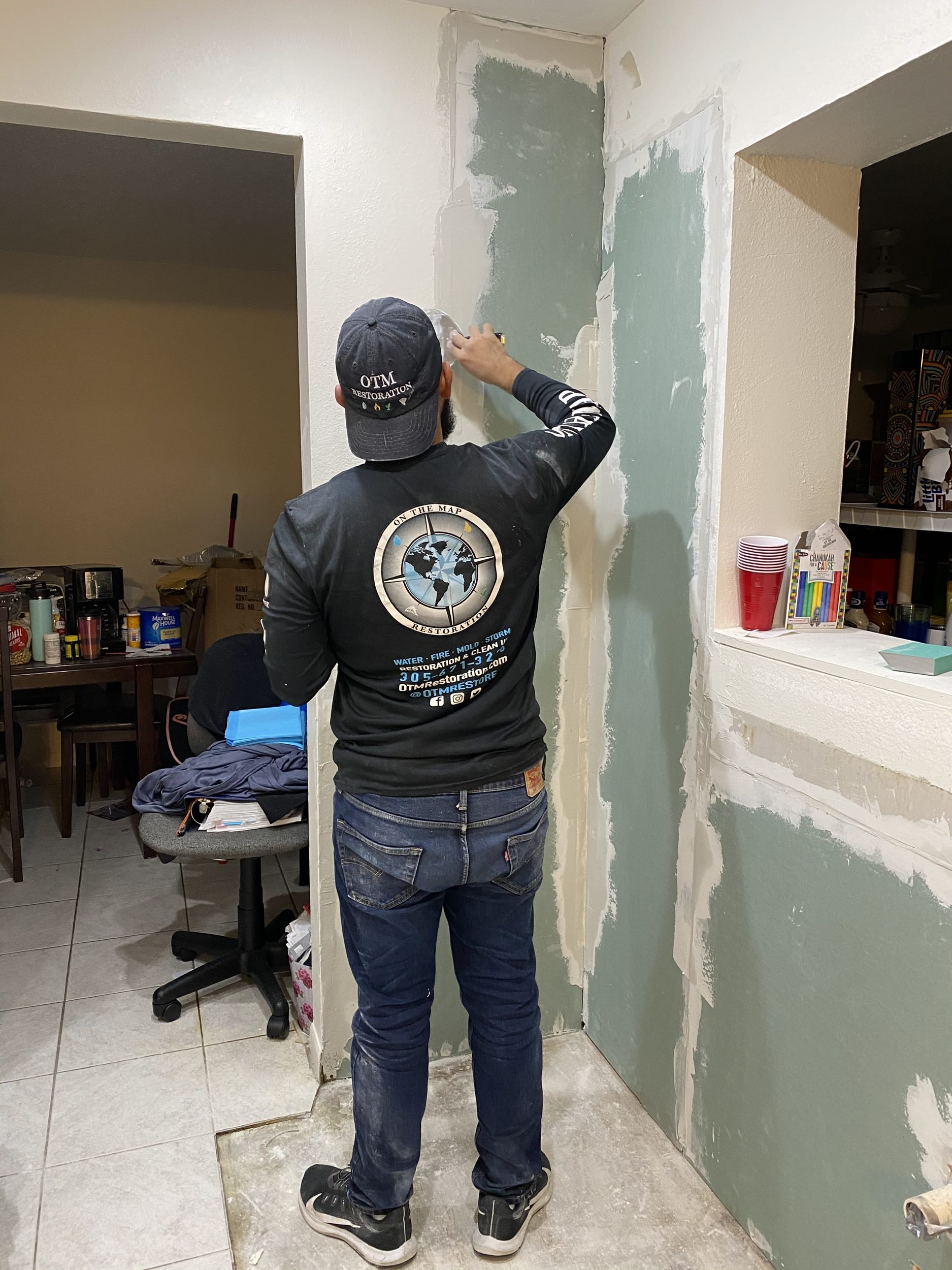 OTM technician finishing drywall repairs after mold remediation