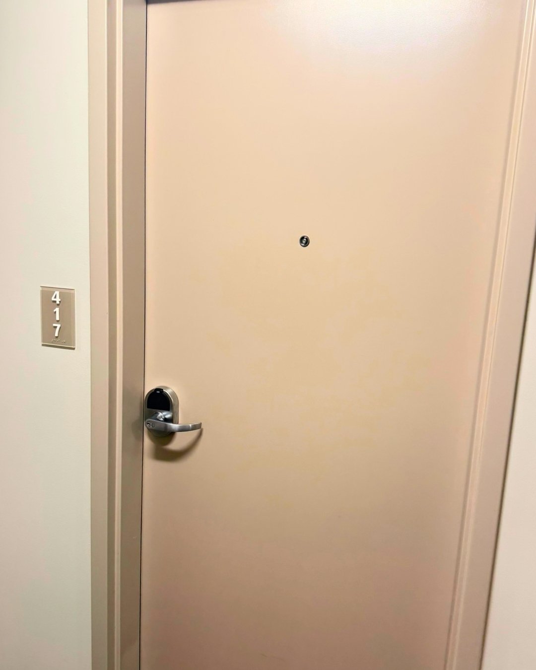 An apartment unit door with a ZeroKey keyless lock and lever handle, next to a unit number sign in the hallway.