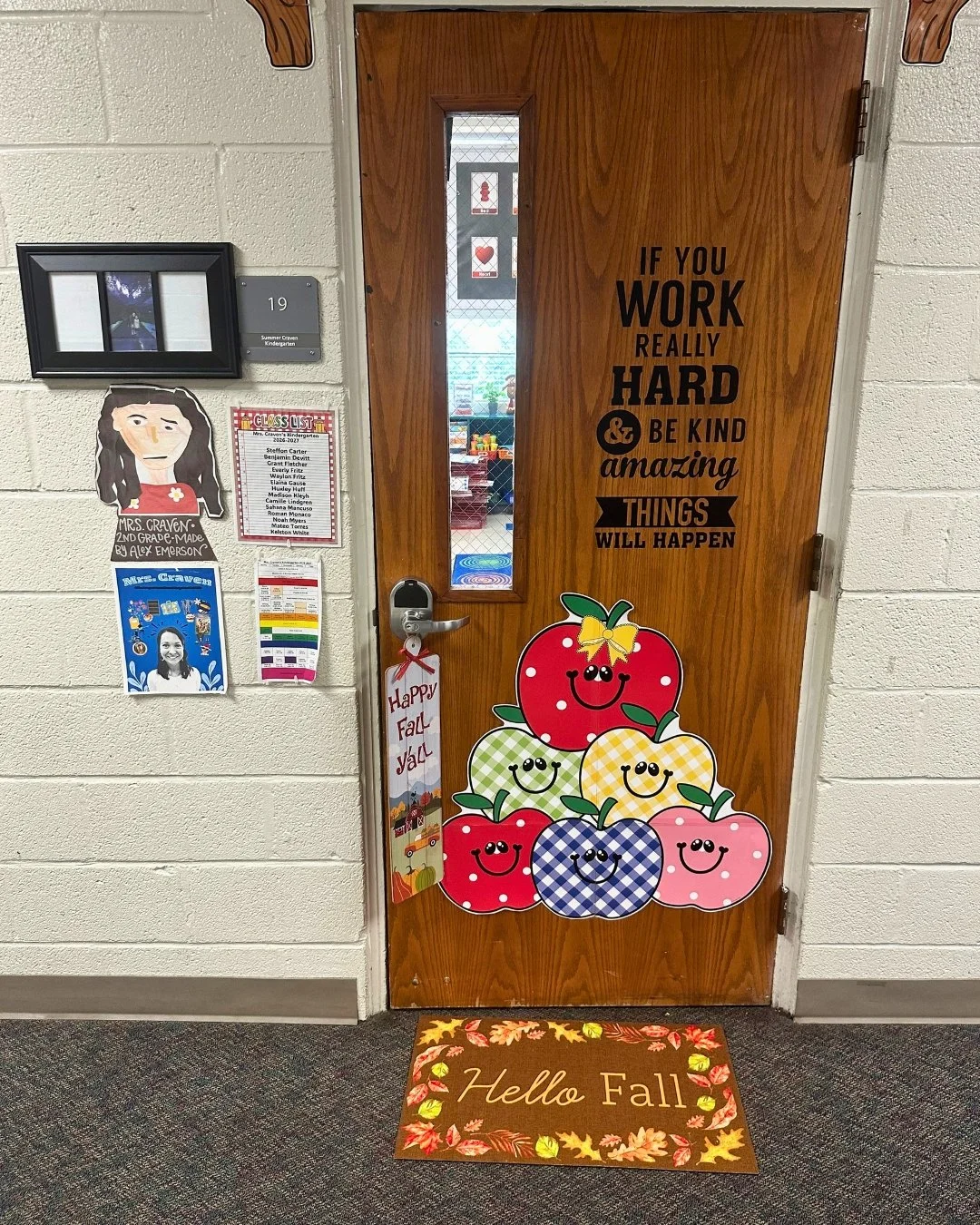 A wooden classroom door decorated with colorful seasonal artwork in a school hallway.