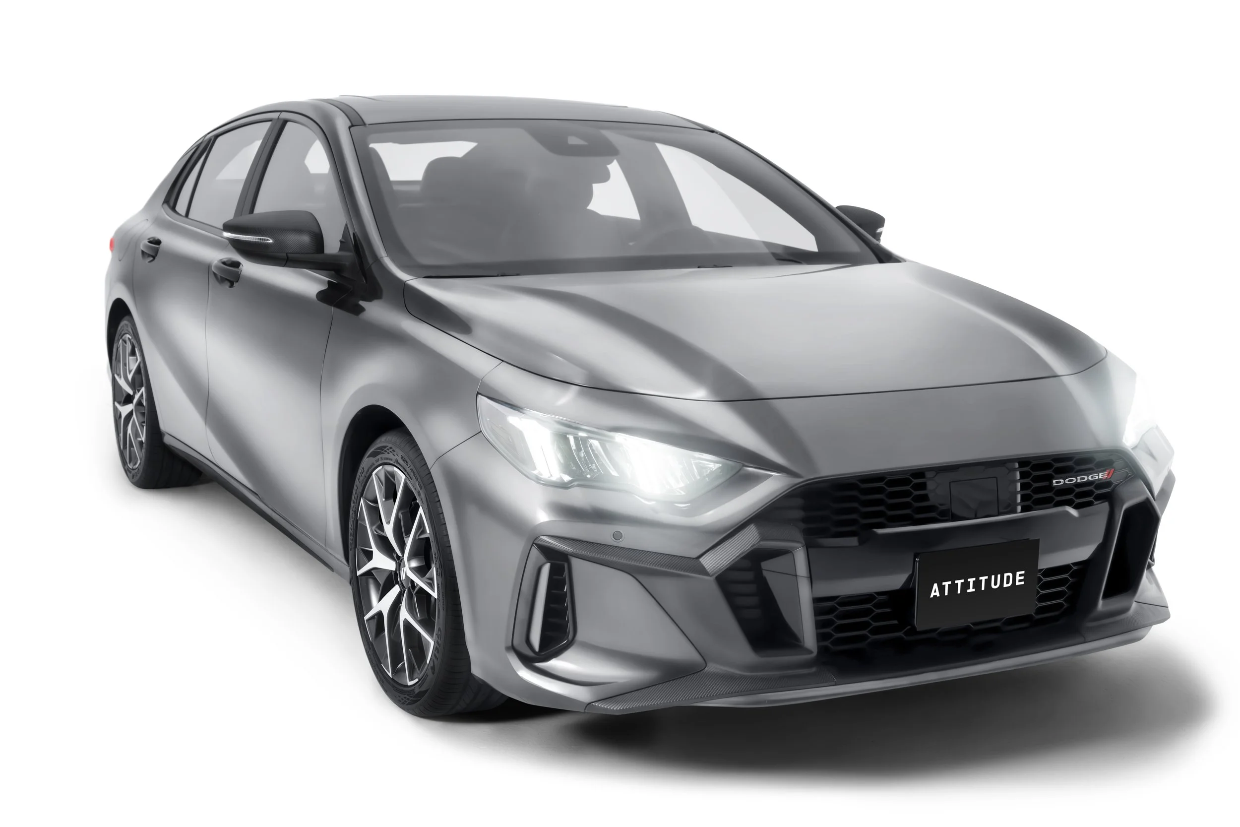 A silver modern compact hatchback car with black accents, alloy wheels, and front license plate reading "ATTITUDE" in a studio setting with a white background.