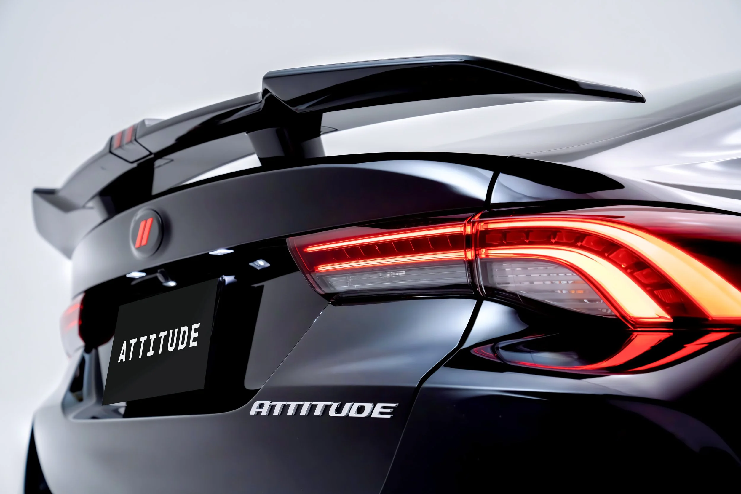 Close-up image of the rear part of a sleek, black and gray helmet with red taillights and the word 'ATTITUDE' written on it.