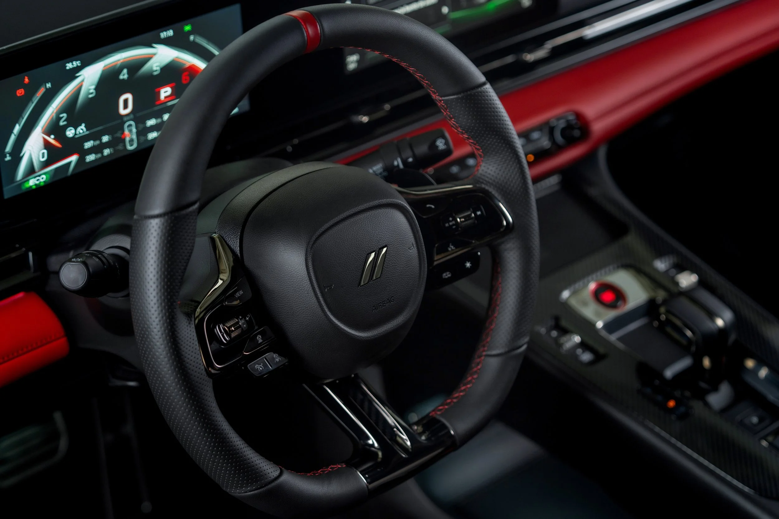 Close-up of a luxury car's interior showing a modern digital dashboard and a black steering wheel with red accents and stitching.