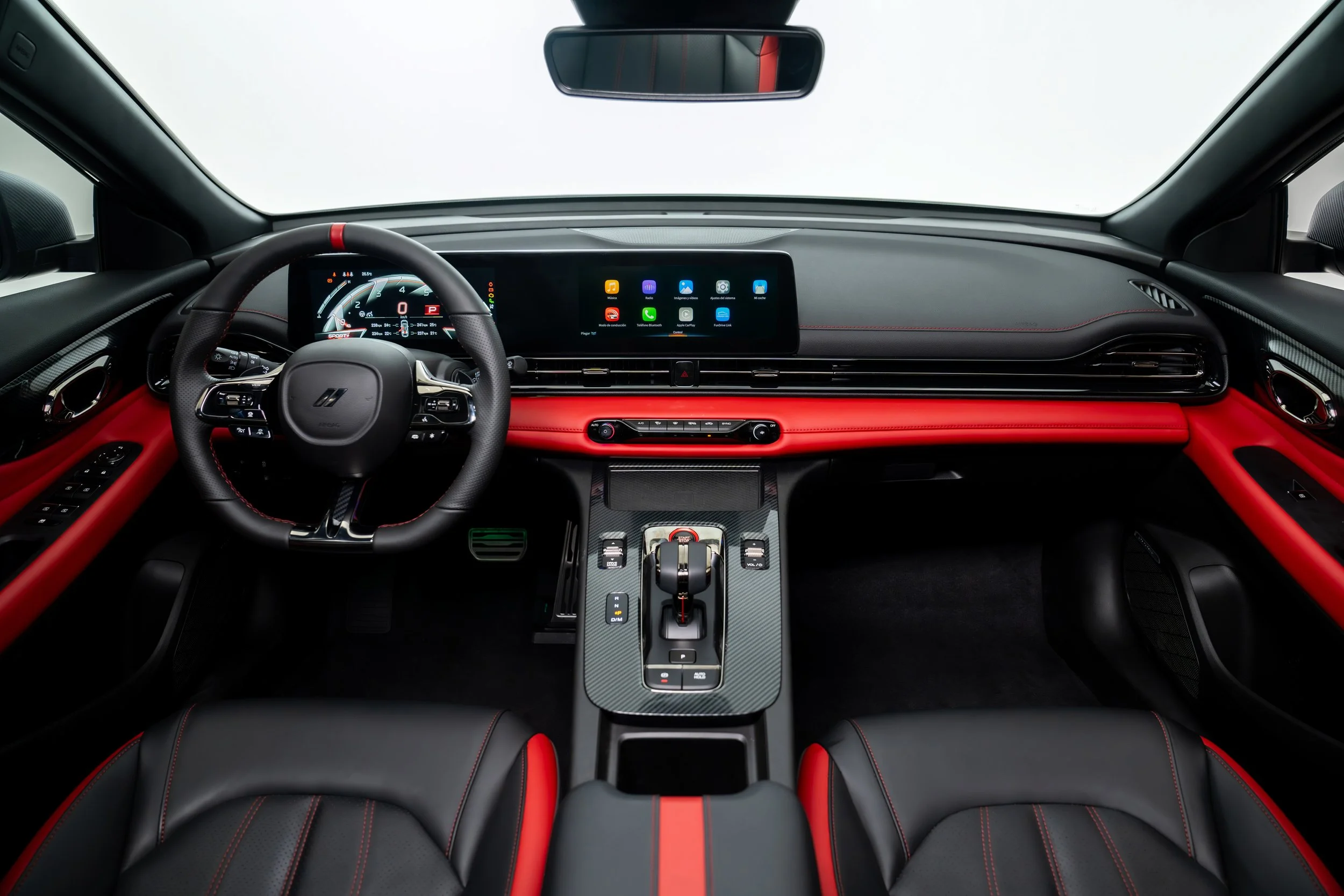 The interior of a modern sports car with a black and red leather dashboard, a digital instrument cluster, a large touchscreen display, and a gear shifter in the center console.