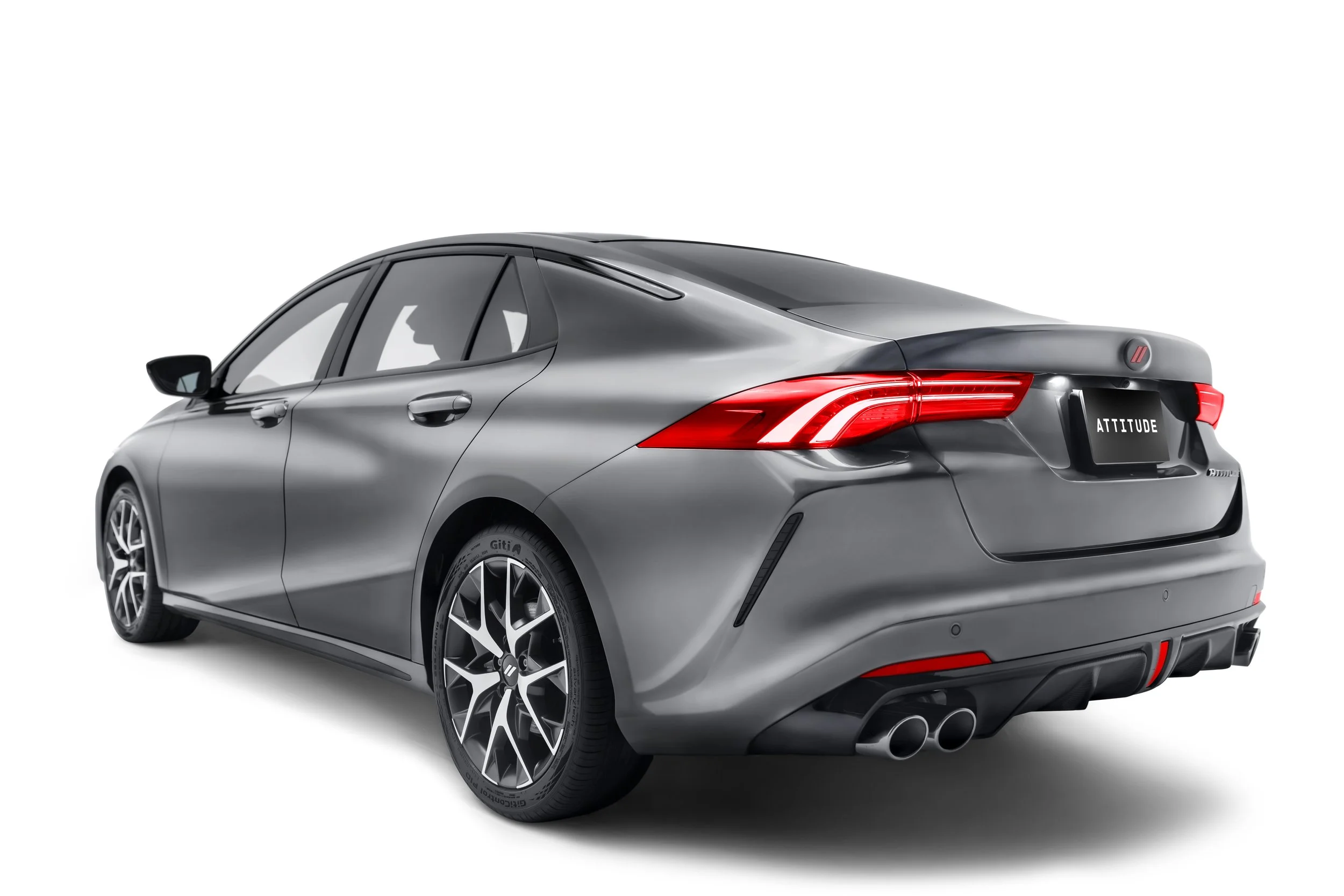 A sleek silver sedan with modern aerodynamic design, large alloy wheels, tinted windows, red taillights, and dual exhaust pipes, labeled with the word 'ATTITUDE' on the license plate, against a white background.