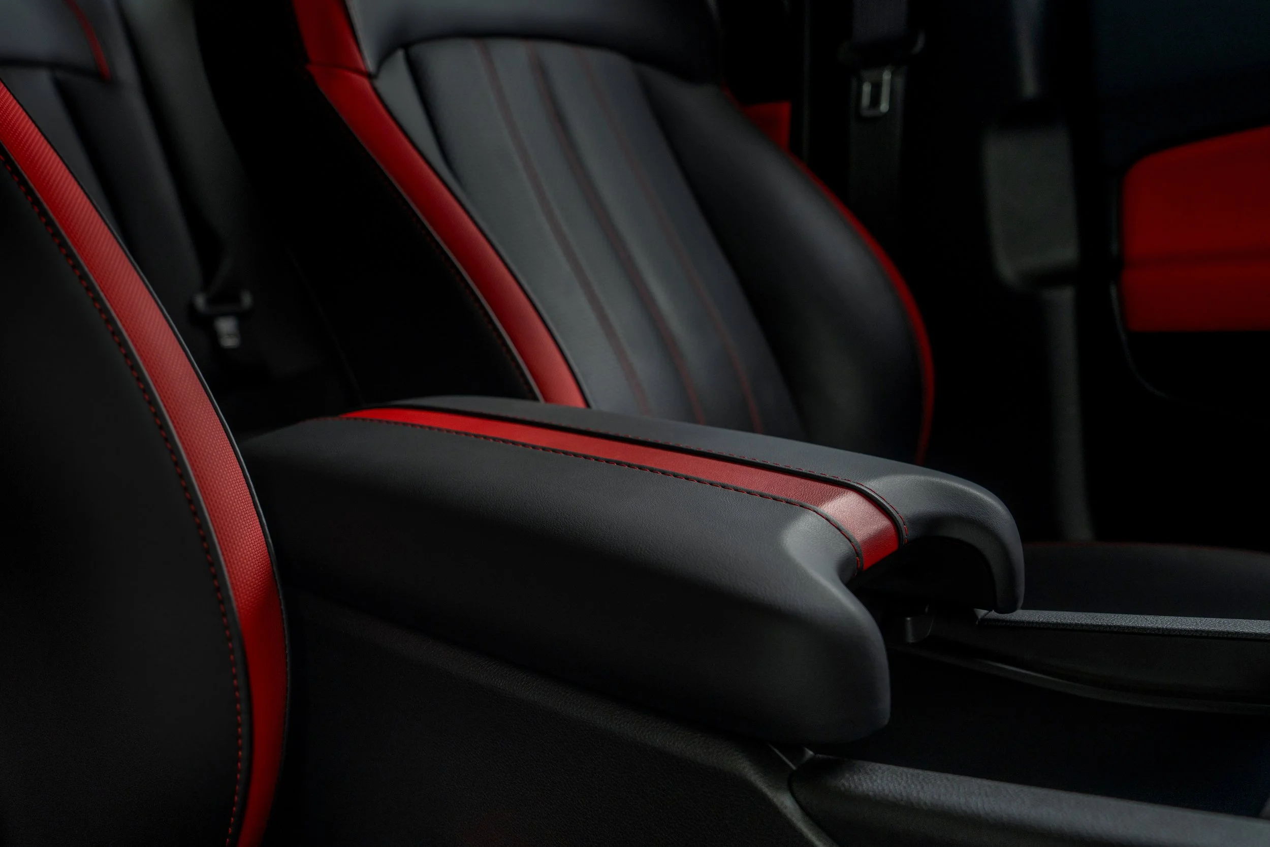Close-up of black and red car interior seats with red stitching.