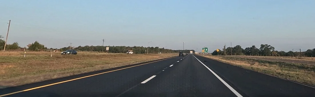 Open highway stretching toward the horizon beneath a wide sky, capturing the start of a solo road trip.