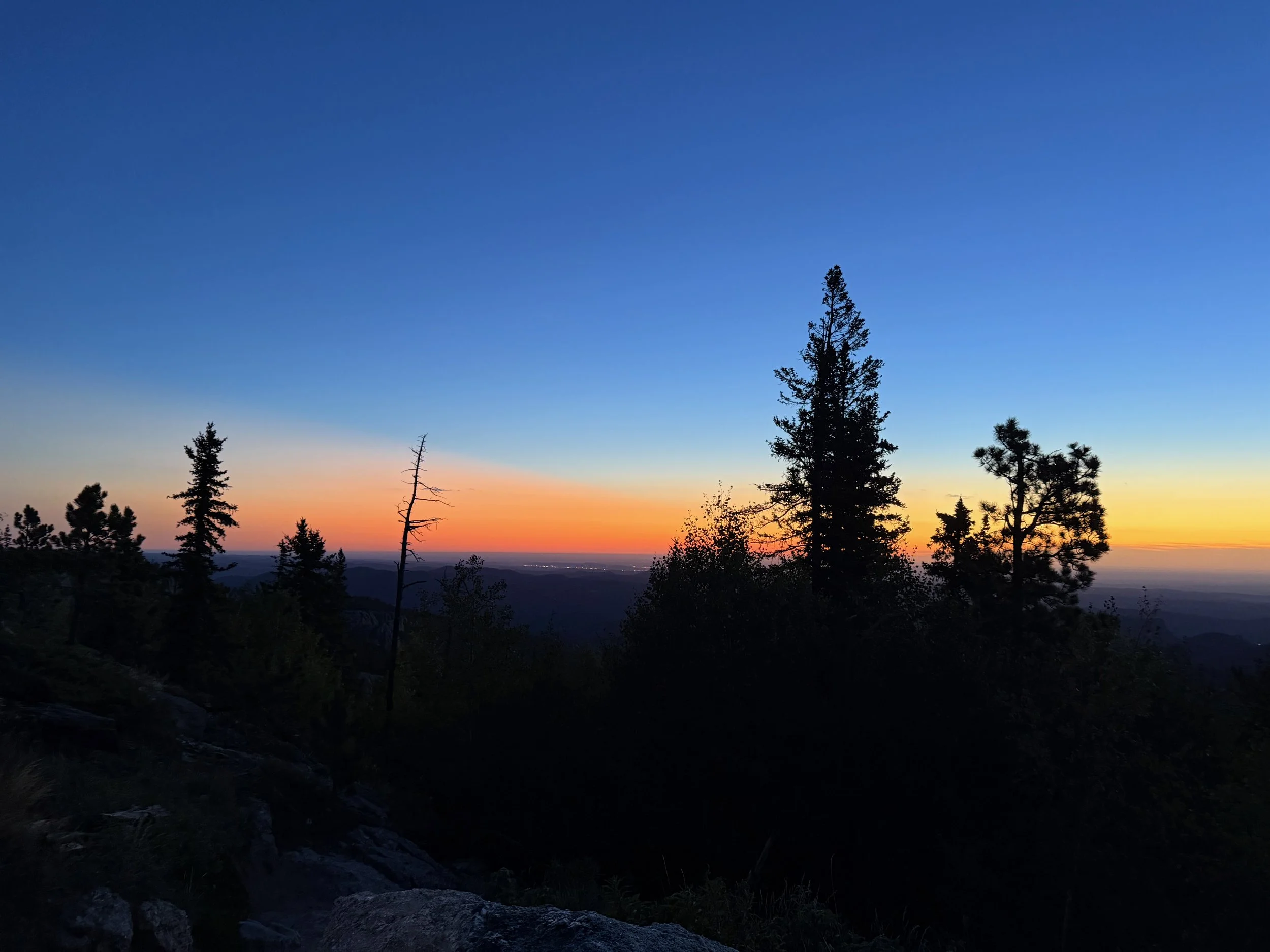 Early morning sky glowing orange above the dark Black Hills landscape.