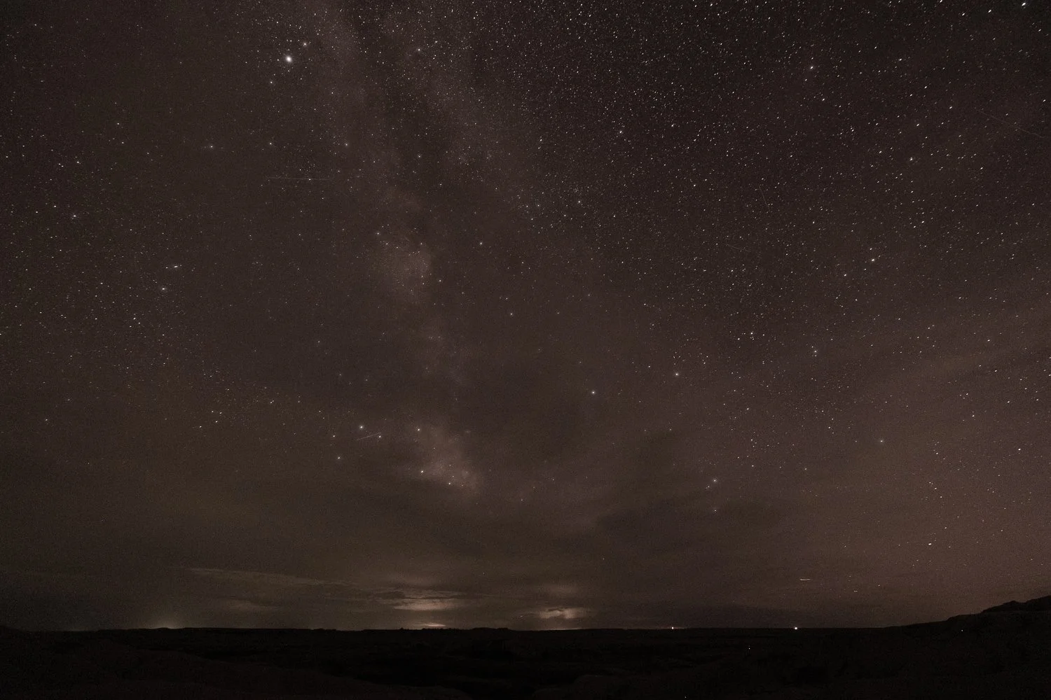 The same night sky after color correction, showing stars and a hint of the Milky Way behind clouds.