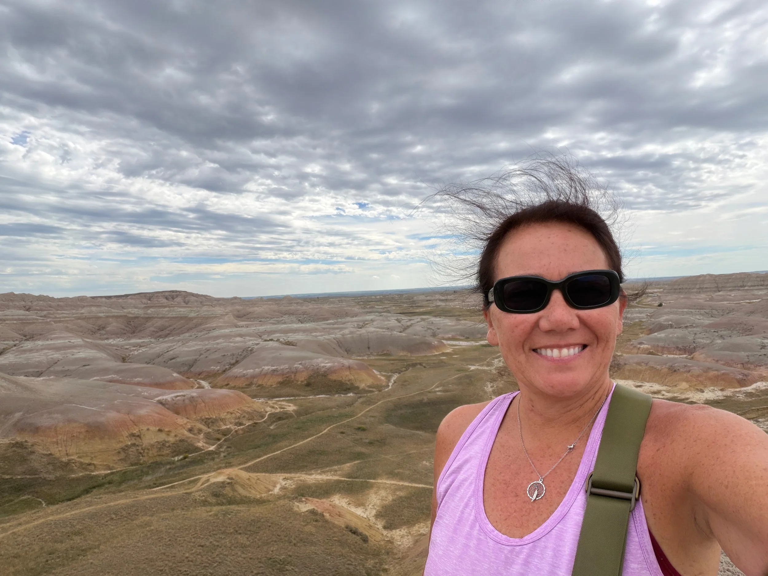 Julie smiling in sunglasses in front of the colorful Yellow Mounds.