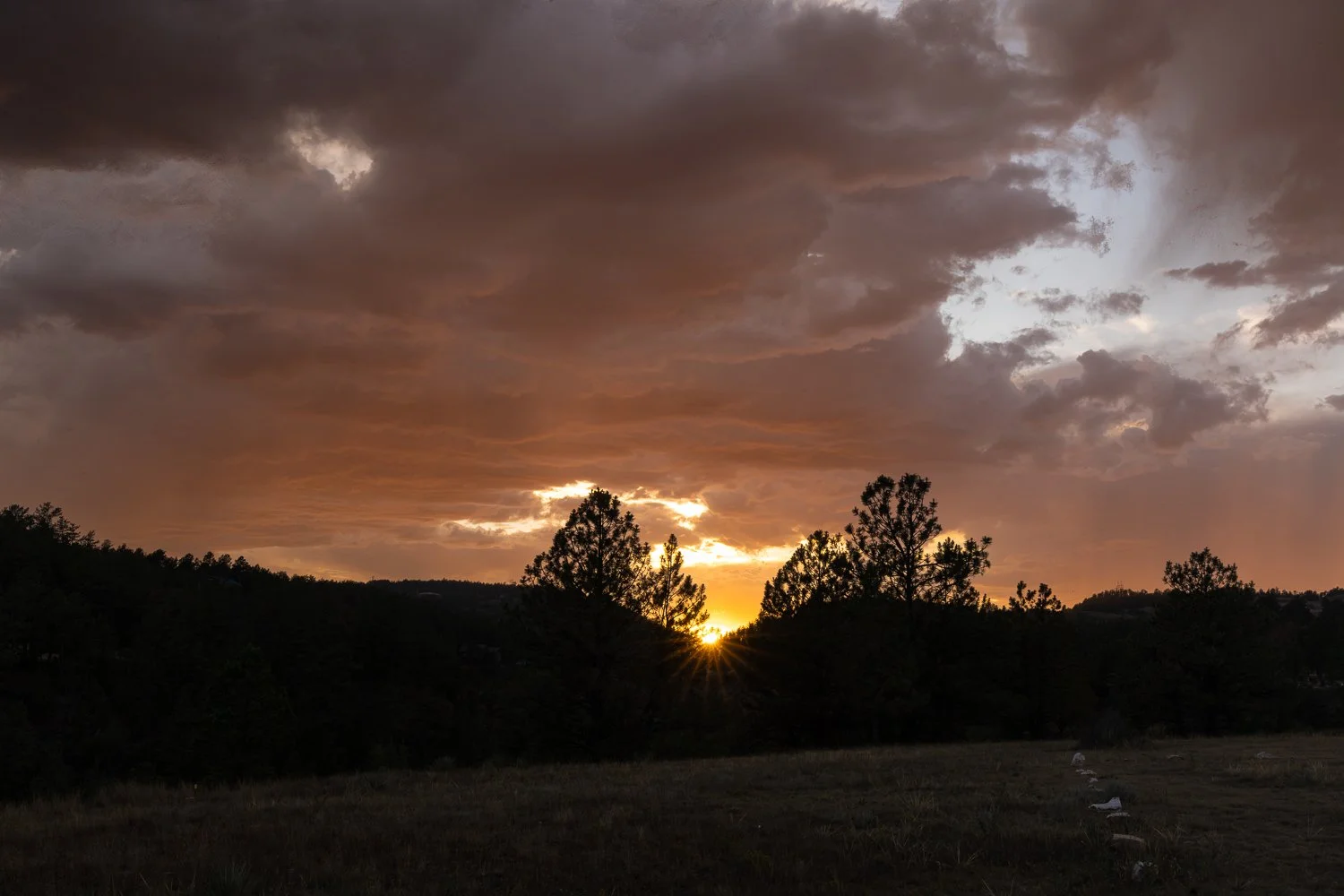 Brilliant sunburst breaks through dark storm clouds over the South Dakota landscape.