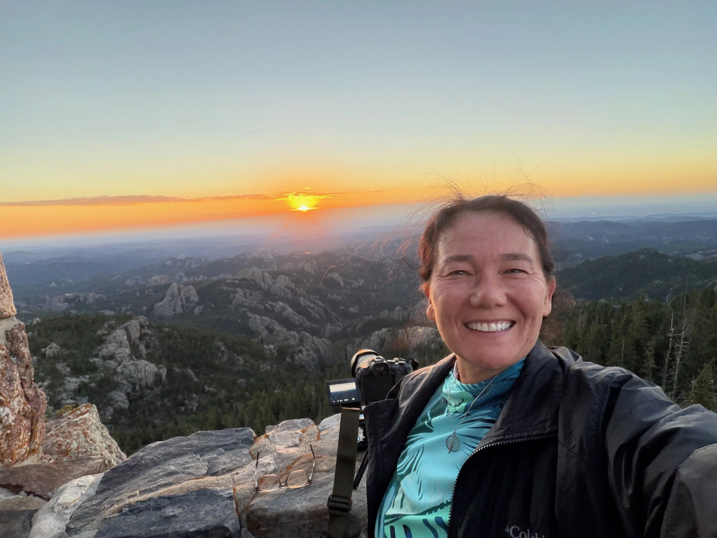Self-portrait at Black Elk Peak with the sunrise and Black Hills landscape behind me.