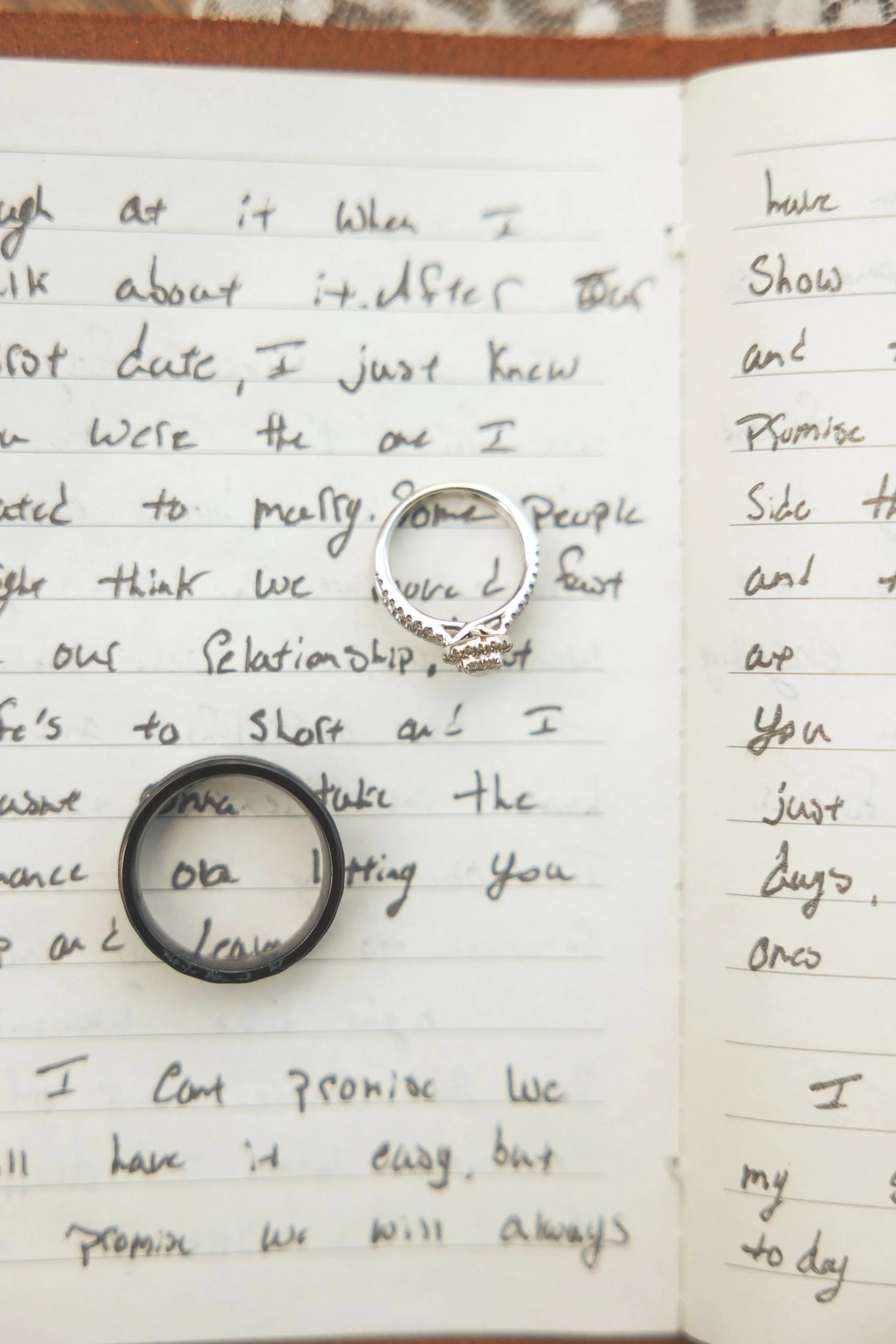 A handwritten note with a silver ring and a black ring placed on it. The note appears to be personal, with cursive writing in black ink on lined paper, and the rings are positioned near the bottom of the note.