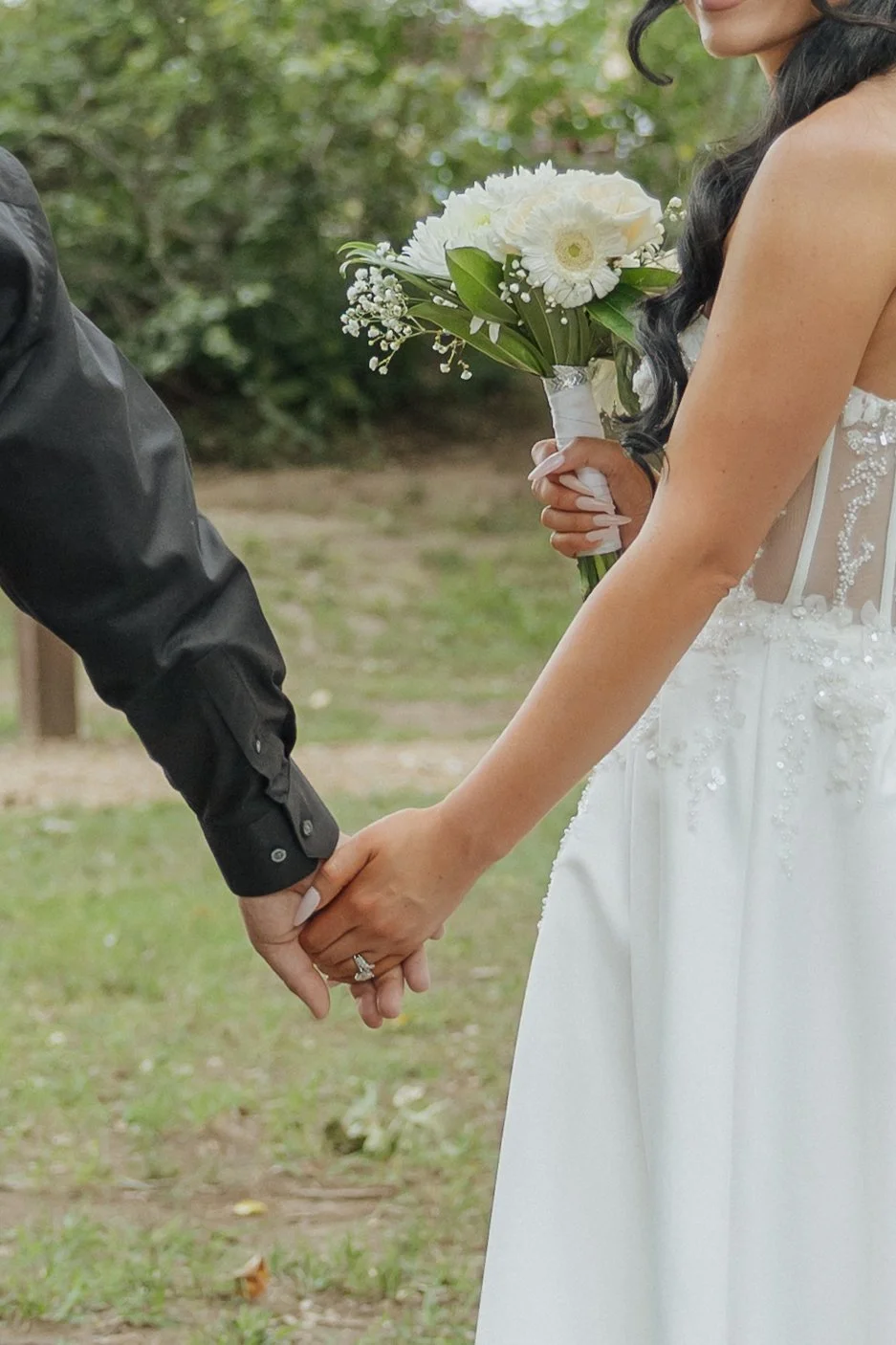 Bride and groom holding hands during a wedding ceremony, with the bride holding a bouquet of white flowers.