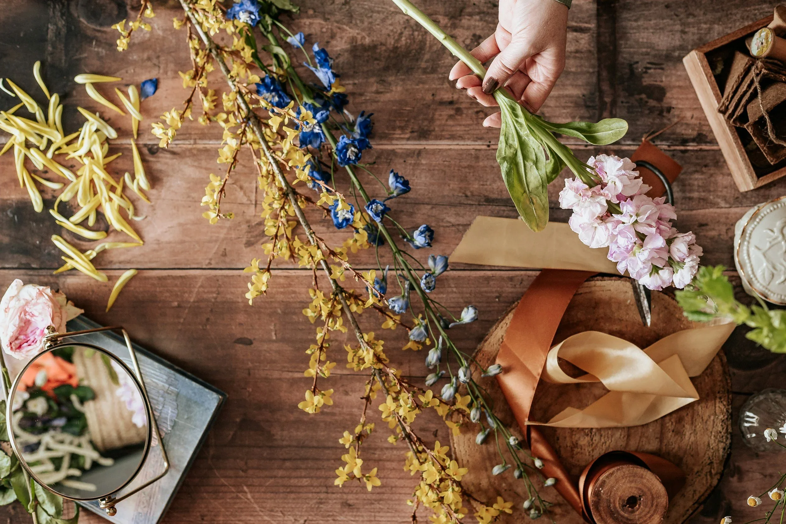 Hands arranging fresh flowers with gold ribbon for an event