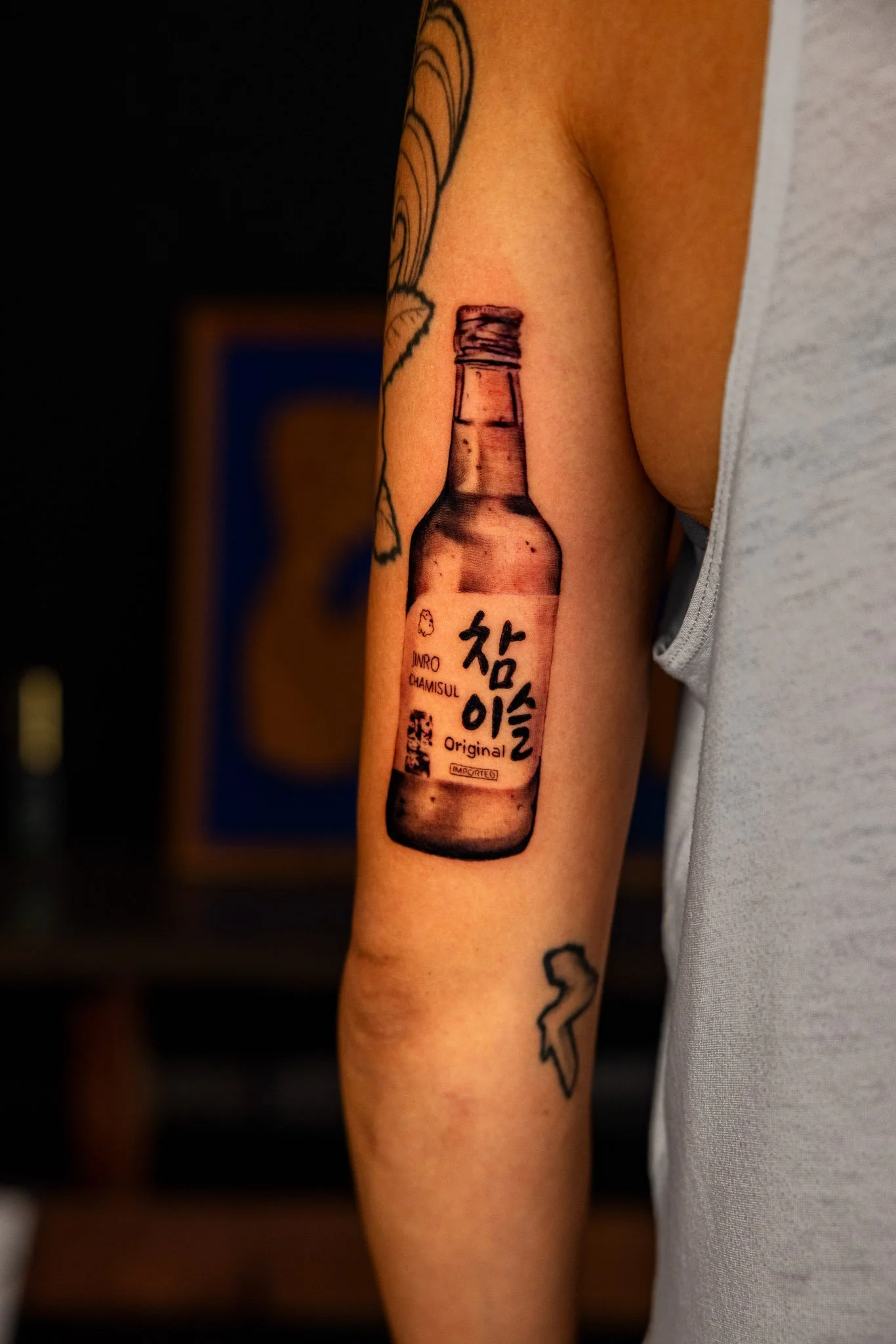 Tattoo of a shoyu bottle on a person's upper arm.