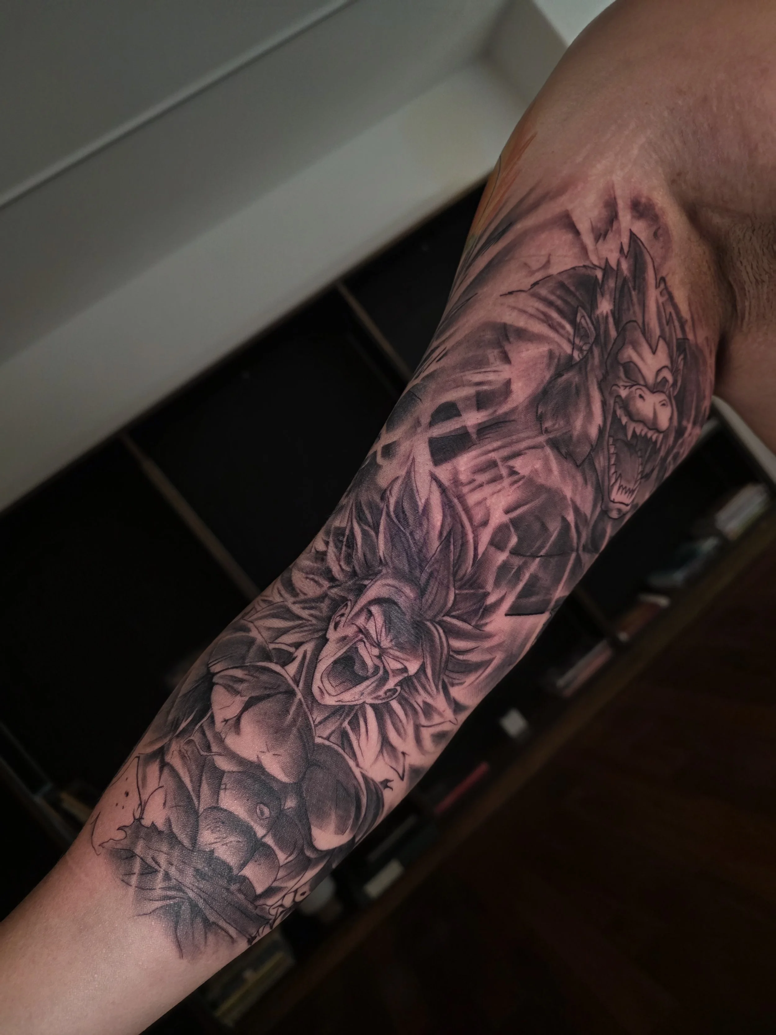 A person's inner bicep with a detailed black and gray tattoo of a fierce Dragon Ball Z piece.