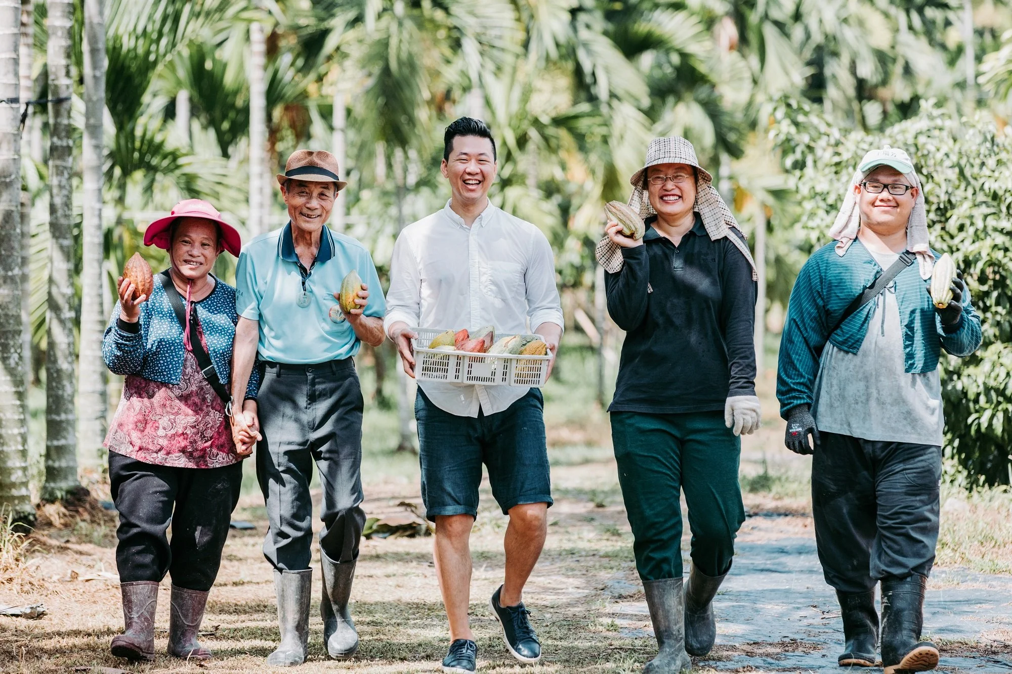 groupe de personnes récoltant du cacao dans une plantation tropicale, tenant des fèves de cacao, souriantes et habillées pour le travail manuel