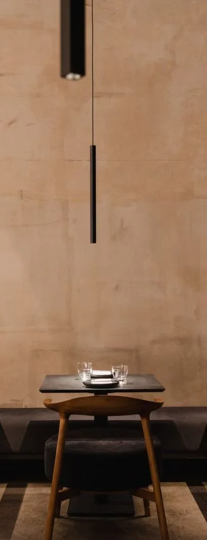 Table élégante avec des verres et des assiettes dans un restaurant, décor minimaliste avec mur en bois et éclairage suspendu