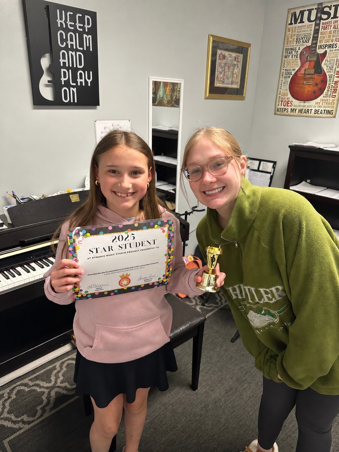 Student and teacher celebrating a music achievement beside a piano
