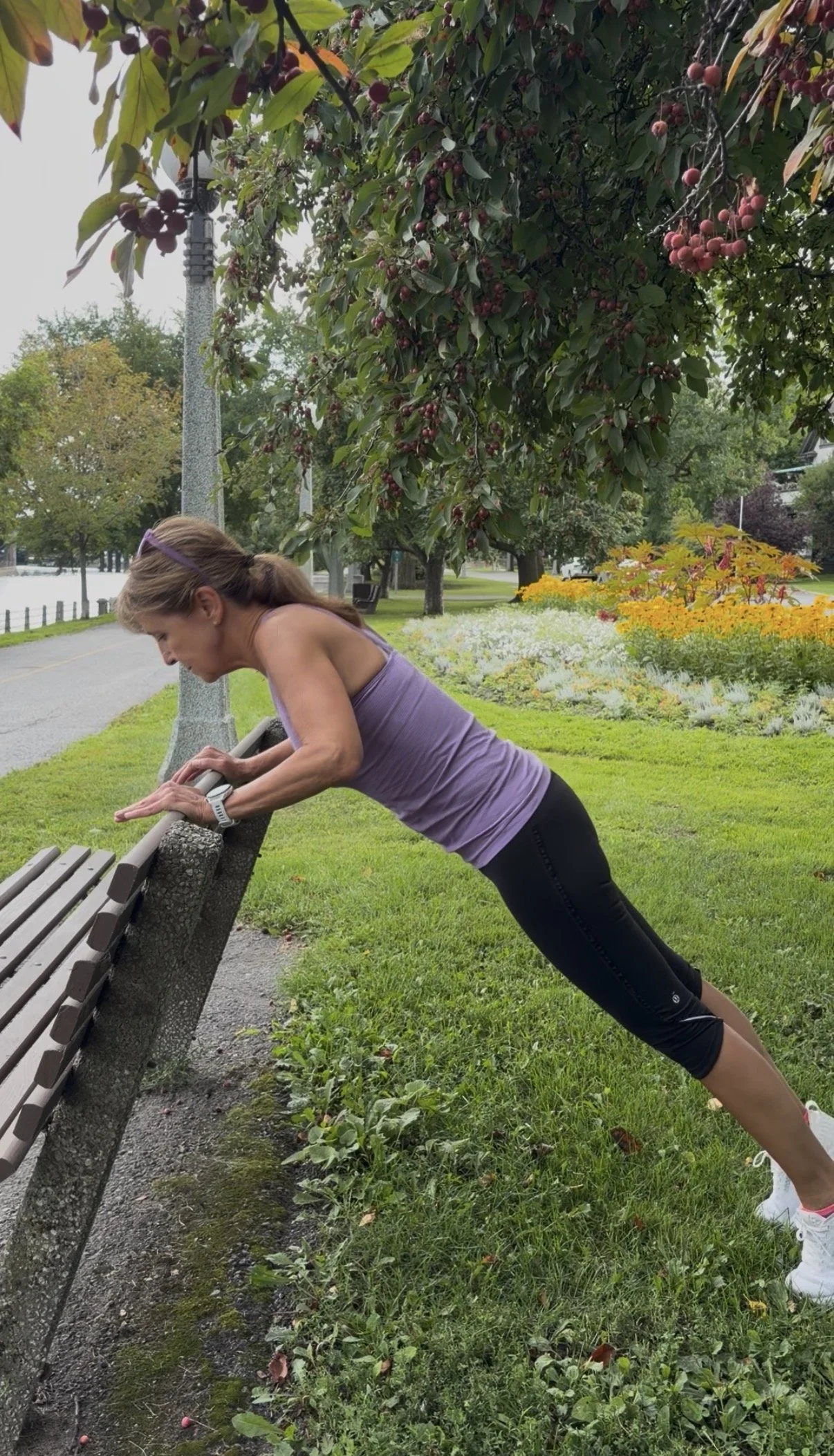 Lisa performing an incline push-up off the top of a park bench during an outdoor Fit with Lisa workout.