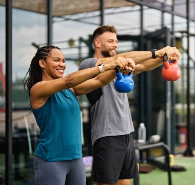 A man and woman holding a kettlebell out in front of their chests with straight arms during a strength workout with Fit with Lisa