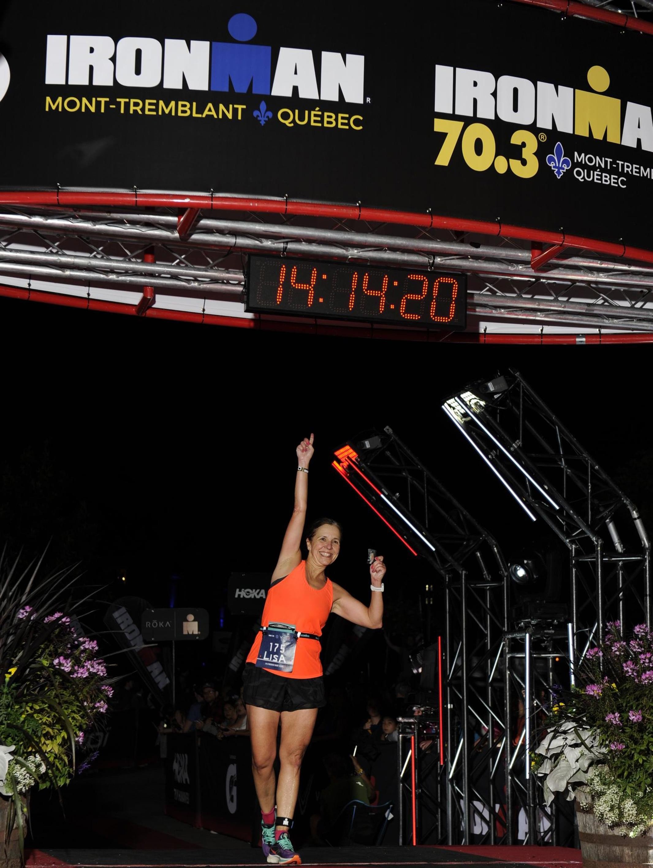 Lisa crossing the finish line at Ironman Mont-Tremblant with a time of 13:40, demonstrating elite endurance expertise for Fit with Lisa coaching.