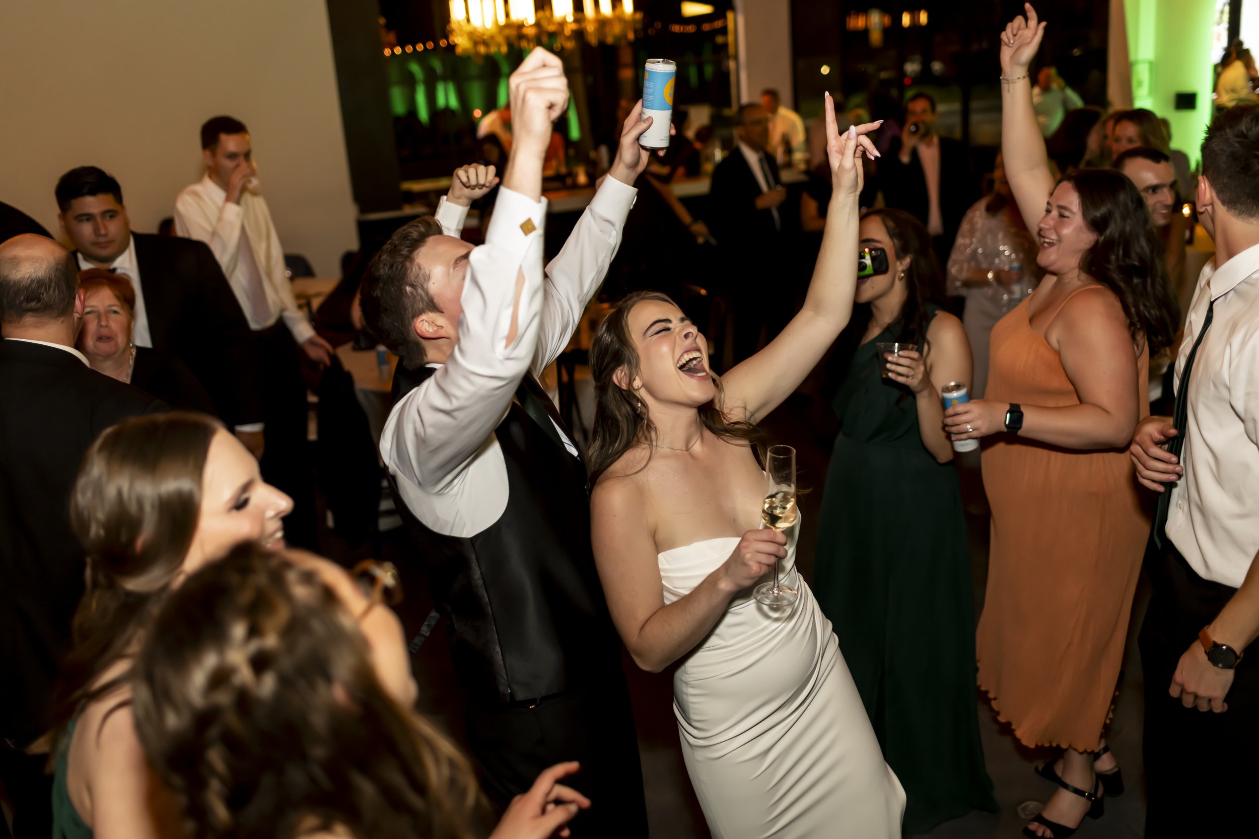 Wedding guests celebrating on a packed dance floor during the reception