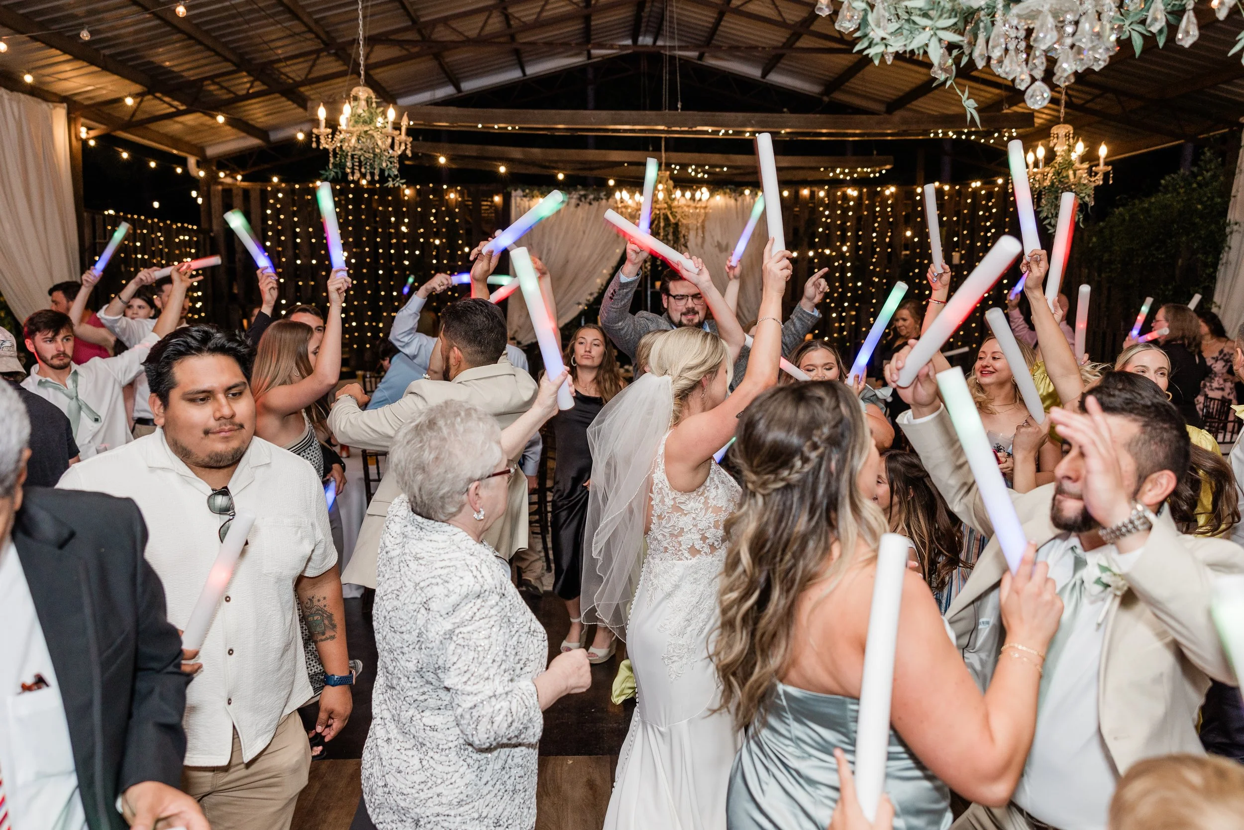 Wedding guests celebrating with glow sticks on a packed dance floor