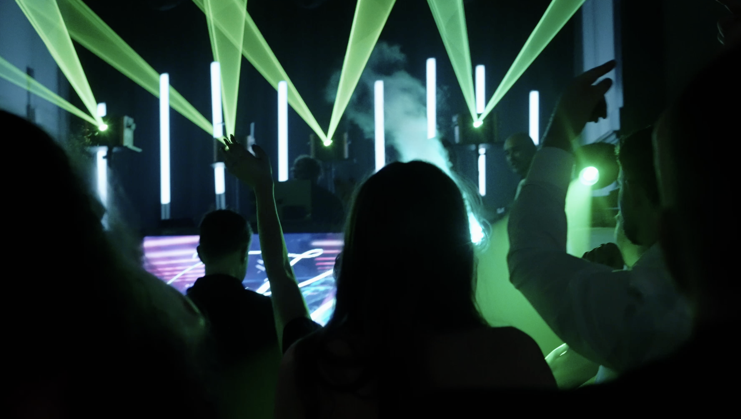 Wedding guests dancing beneath immersive laser lighting during a reception